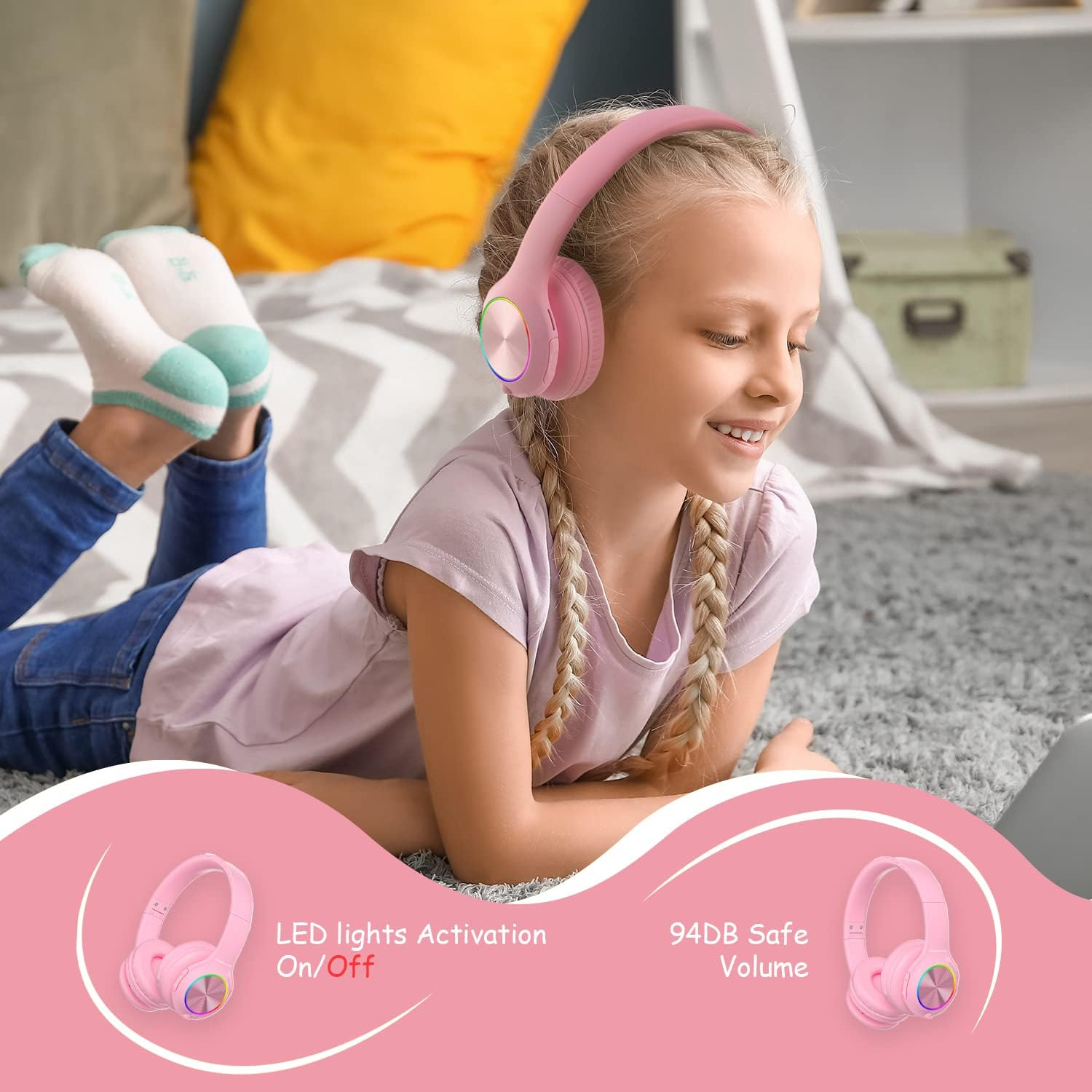 Fille avec casque rose allongée sur tapis regardant ordinateur.