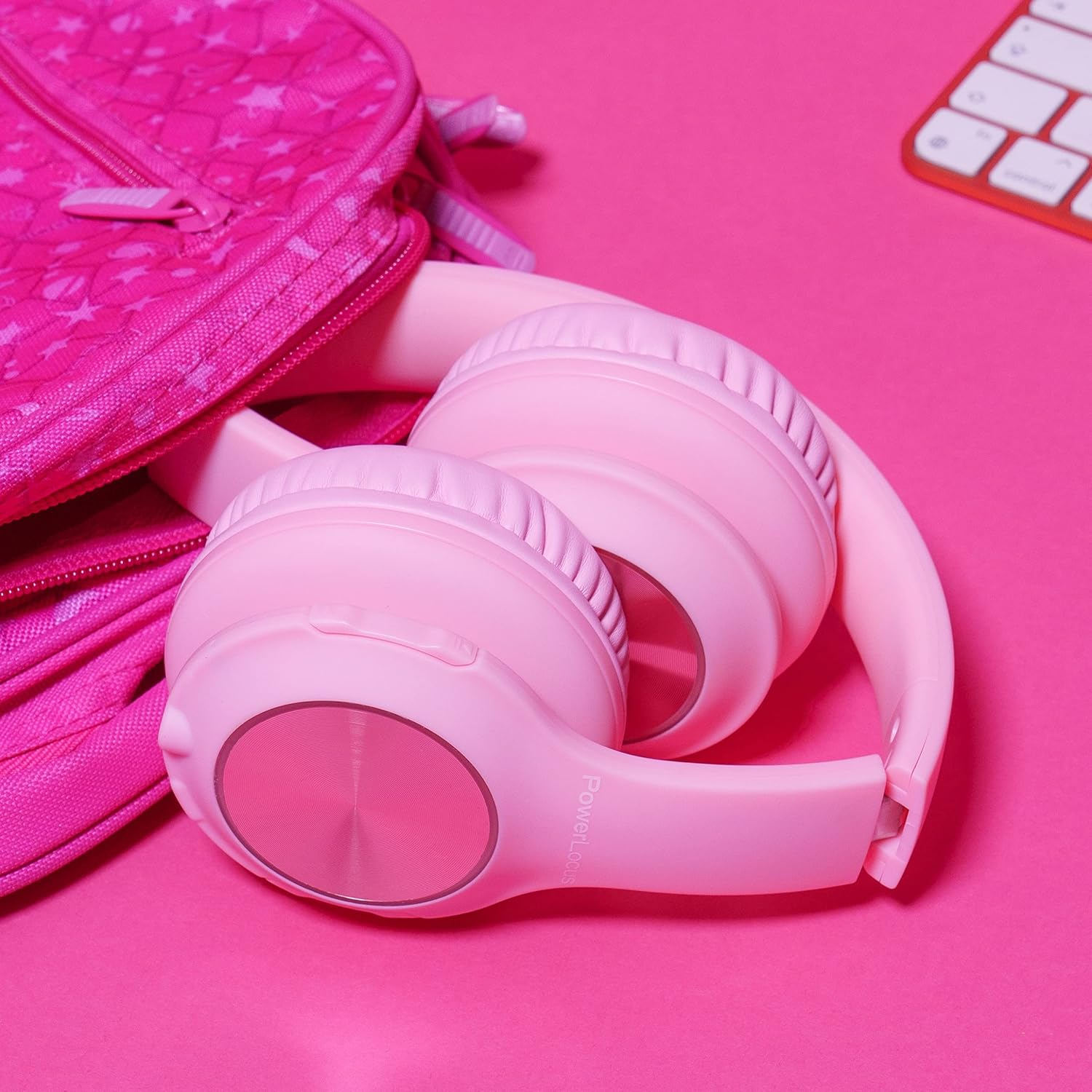 Un sac à dos rose à étoiles et un casque rose à côté sur fond rose.