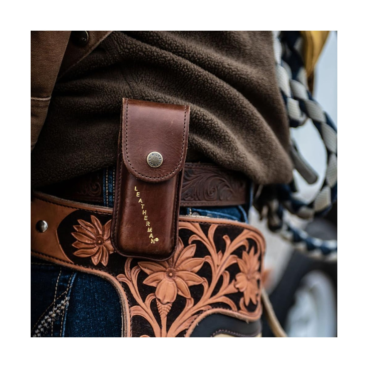 Braune Leder-Leatherman-Tasche an einem verzierten Gürtel mit floraler Schnitzerei.