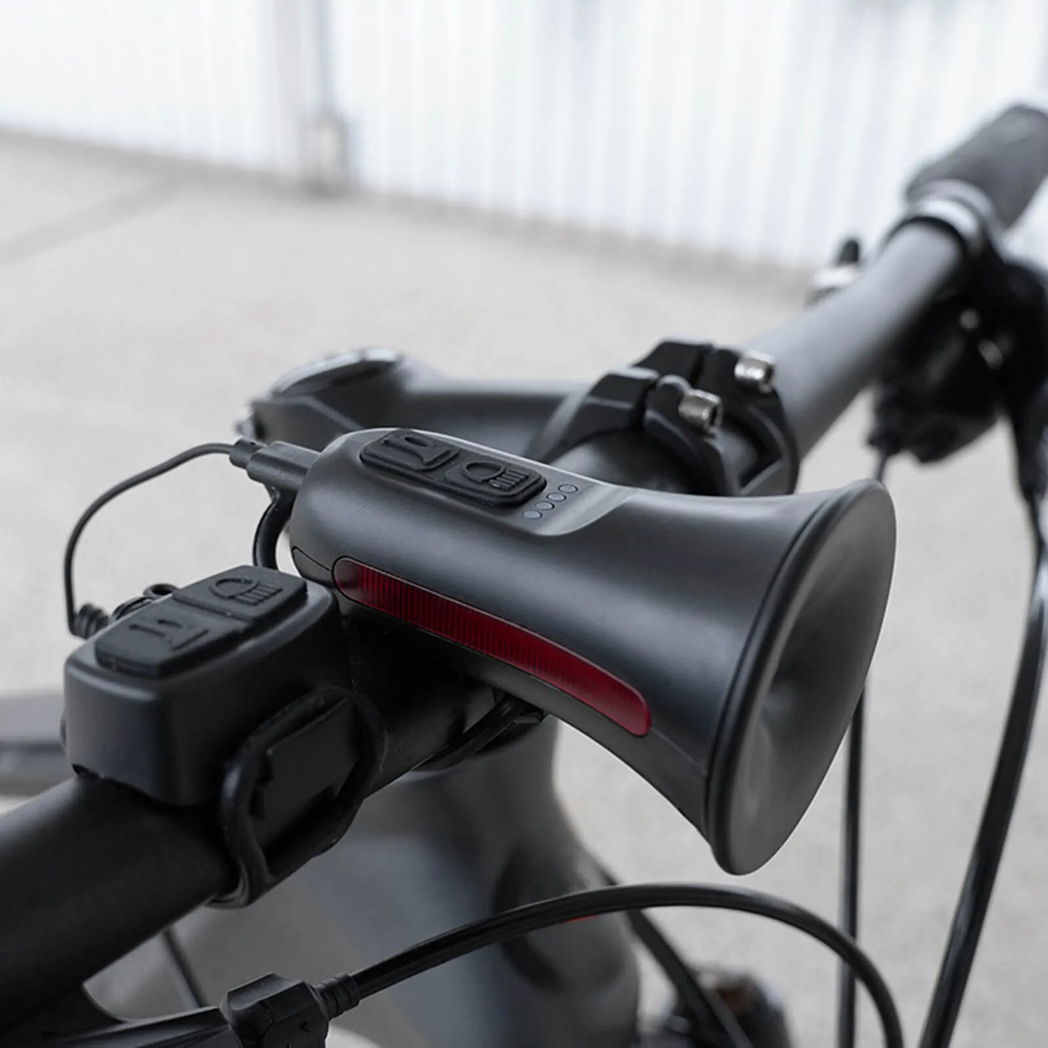Schwarzer Fahrradlenker mit angebrachtem Lautsprecher und rotem Lichtstreifen.