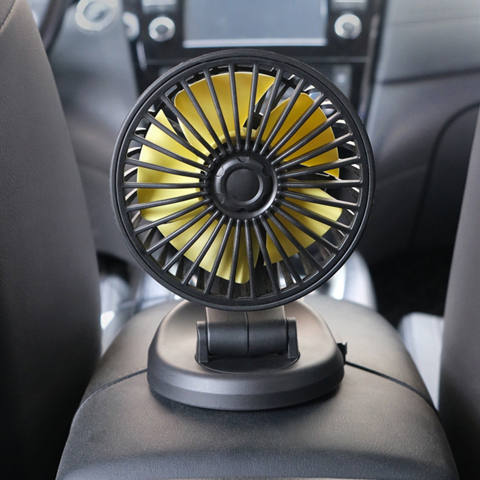 Ein kleiner gelber Ventilator auf einem schwarzen Auto-Armaturenbrett.