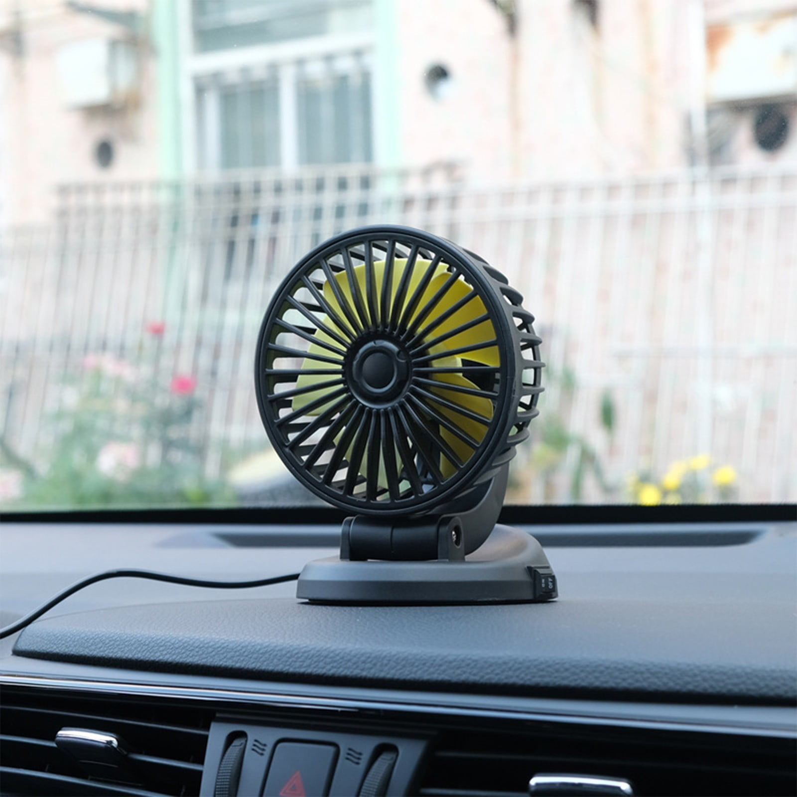 Ein kleiner schwarzer Ventilator mit gelben Rotorblättern sitzt auf dem Armaturenbrett.