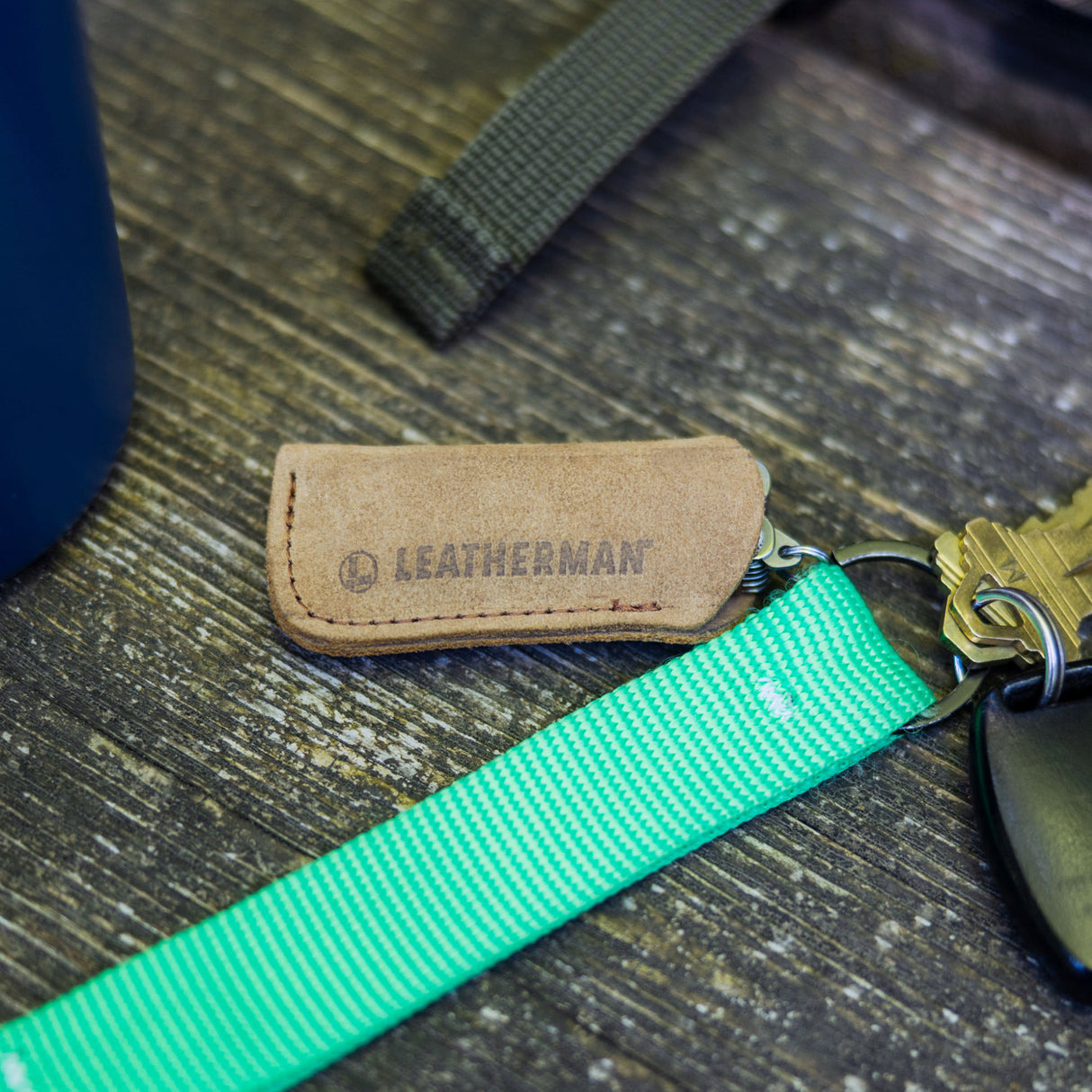 Leatherman-Schlüsselanhänger aus Leder, Schlüsselbund und ein Teil einer blauen Flasche.