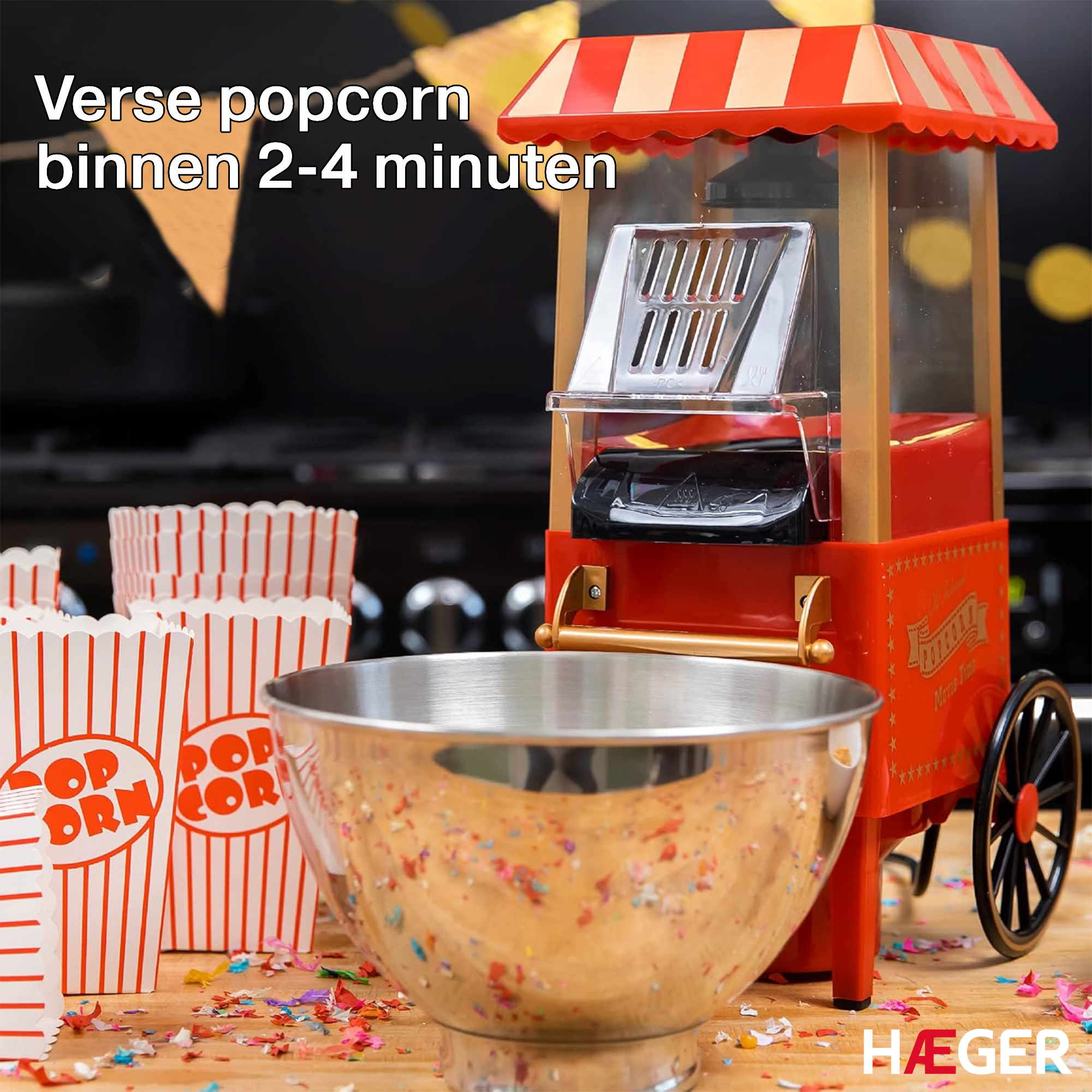 Red popcorn machine with bowl and paper cups, on a wooden table with confetti.