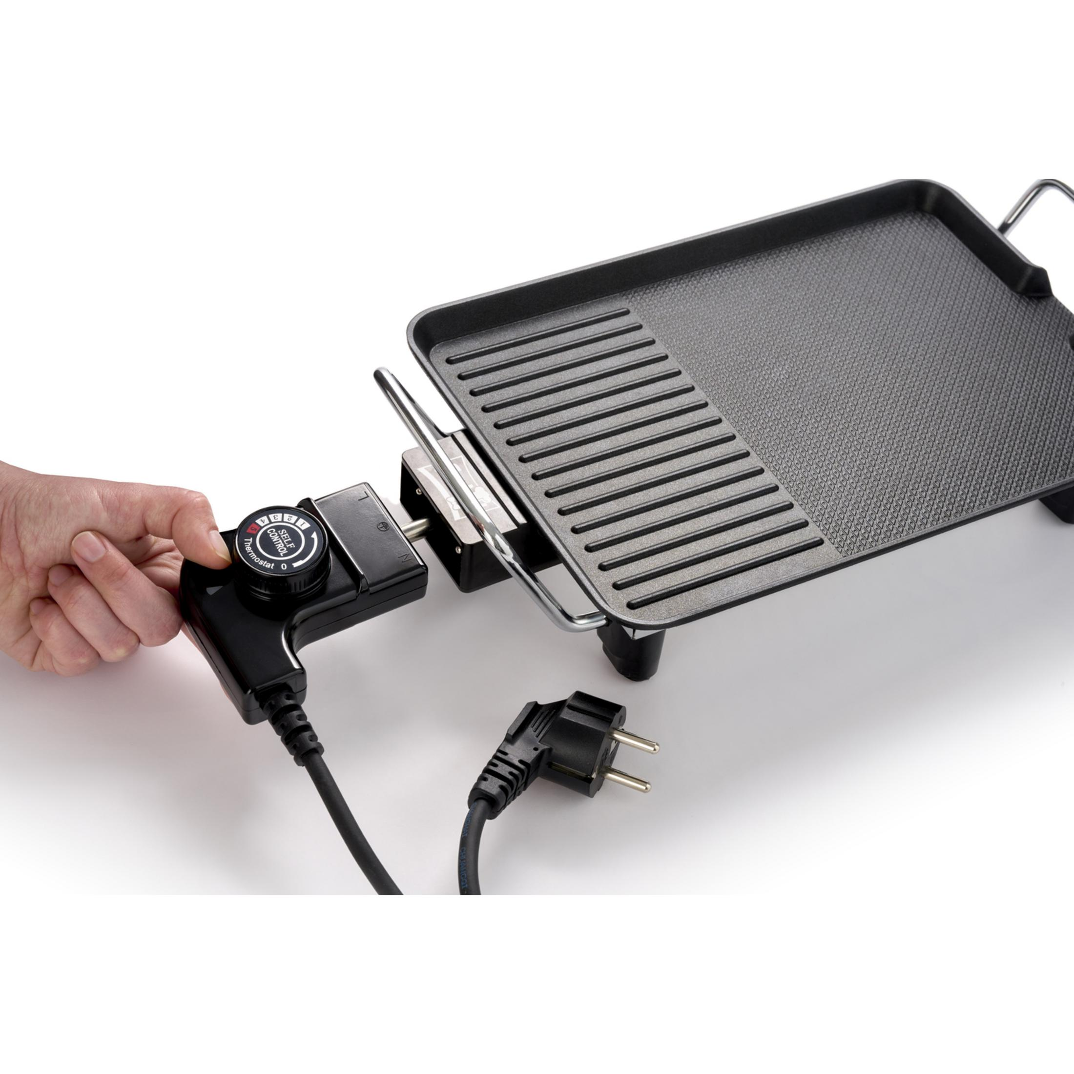 A hand adjusts the temperature control on a black electric grill. A power cord is visible.