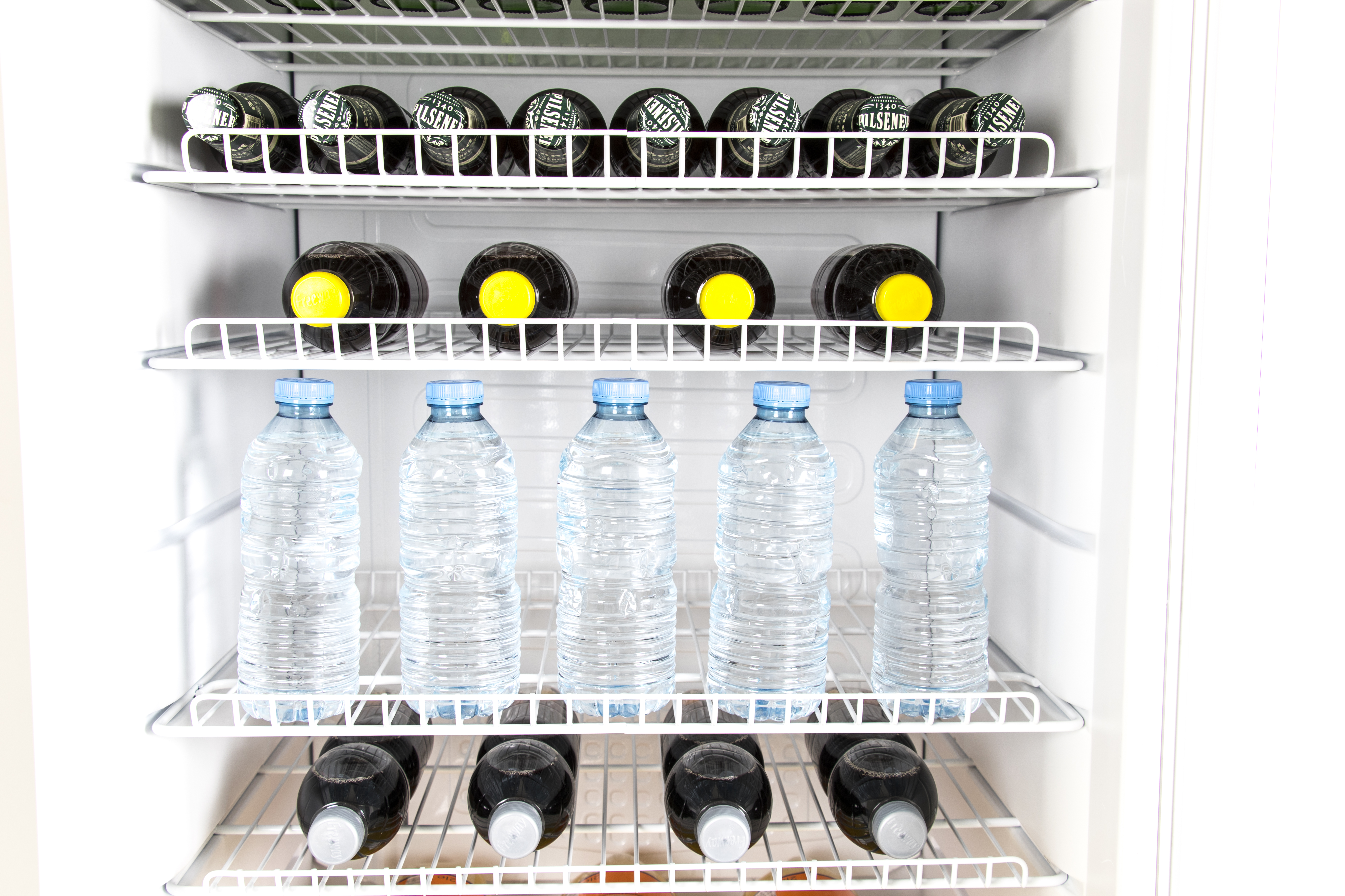 A refrigerator with four shelves, filled with bottles.