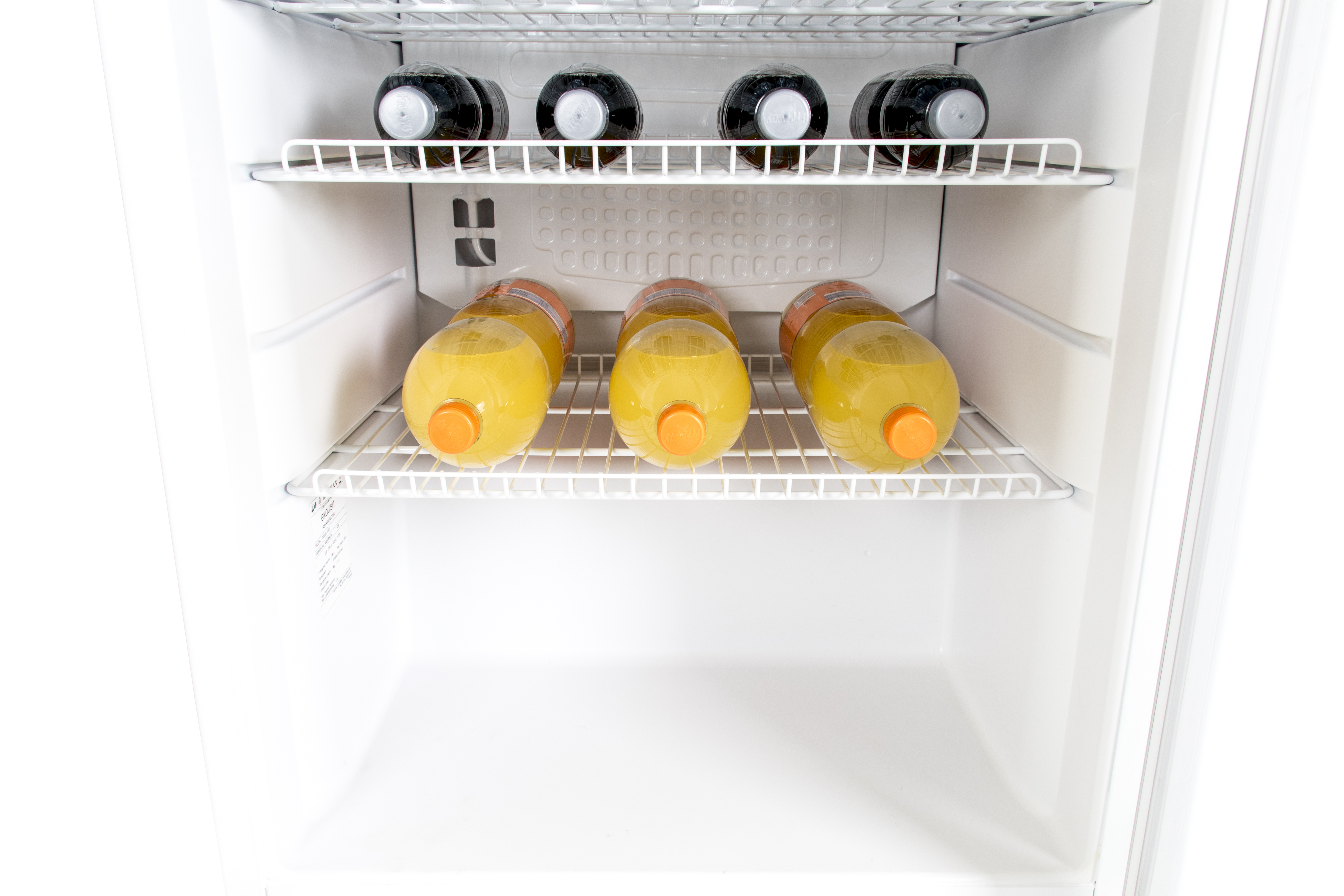 An open white refrigerator with four black and four yellow drink bottles on shelves.