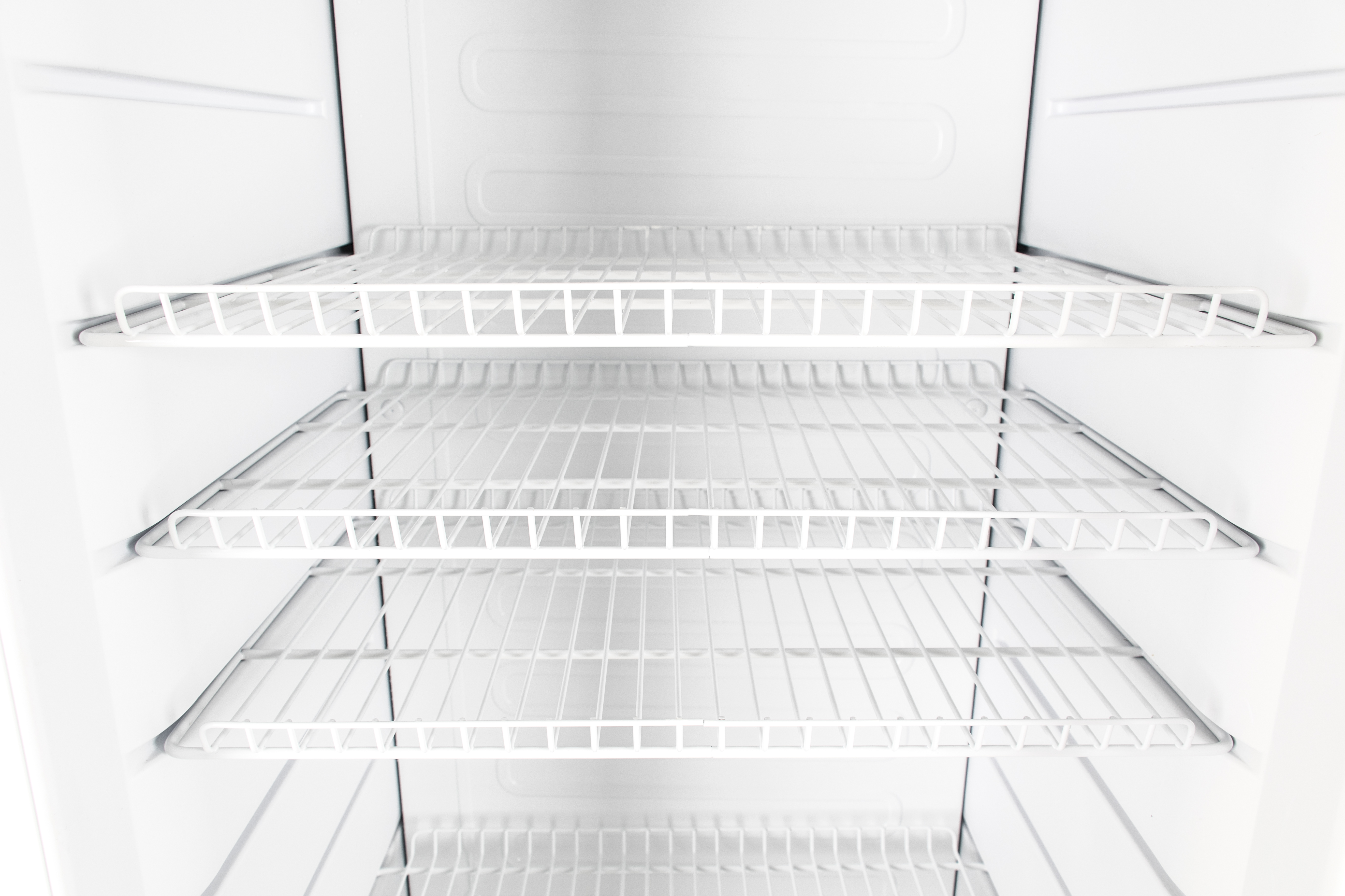 Interior view of an empty white refrigerator with wire shelves.