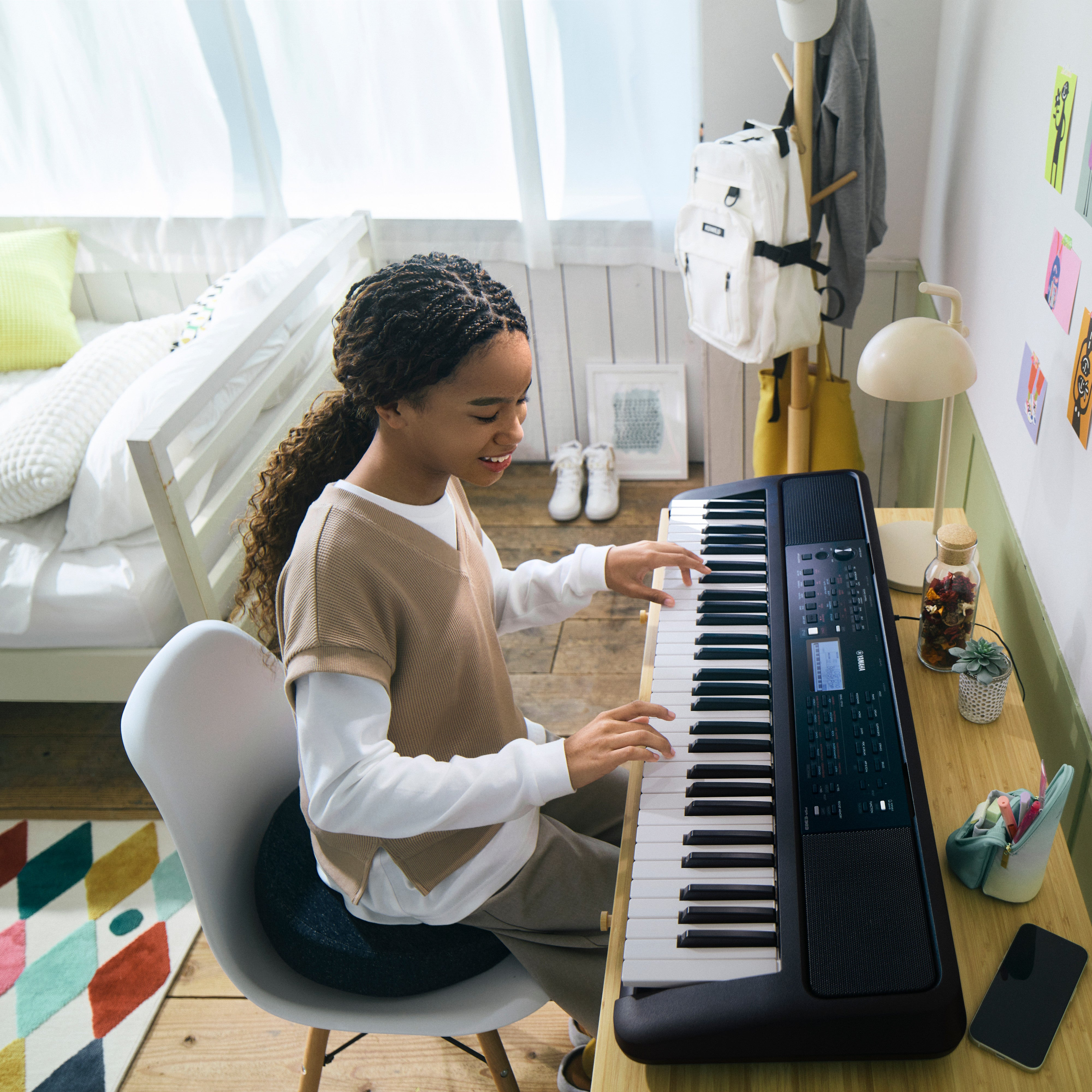 Młoda dziewczyna gra na keyboardzie w jasnym pokoju.