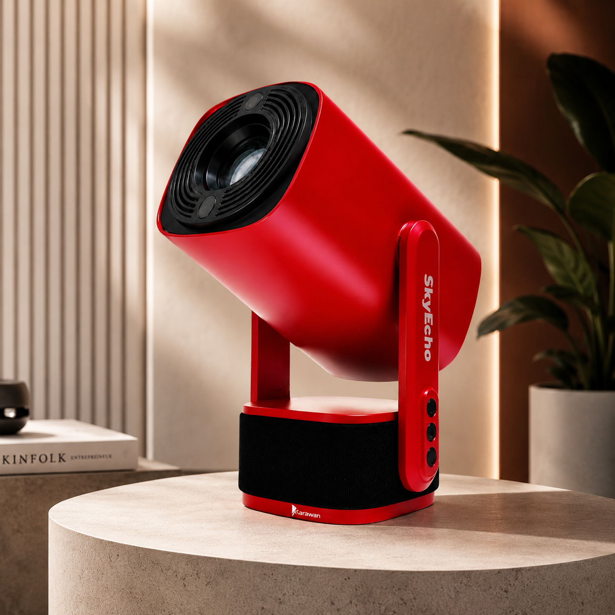 Proyector rojo con altavoz negro sobre una mesa junto a un libro y una planta.