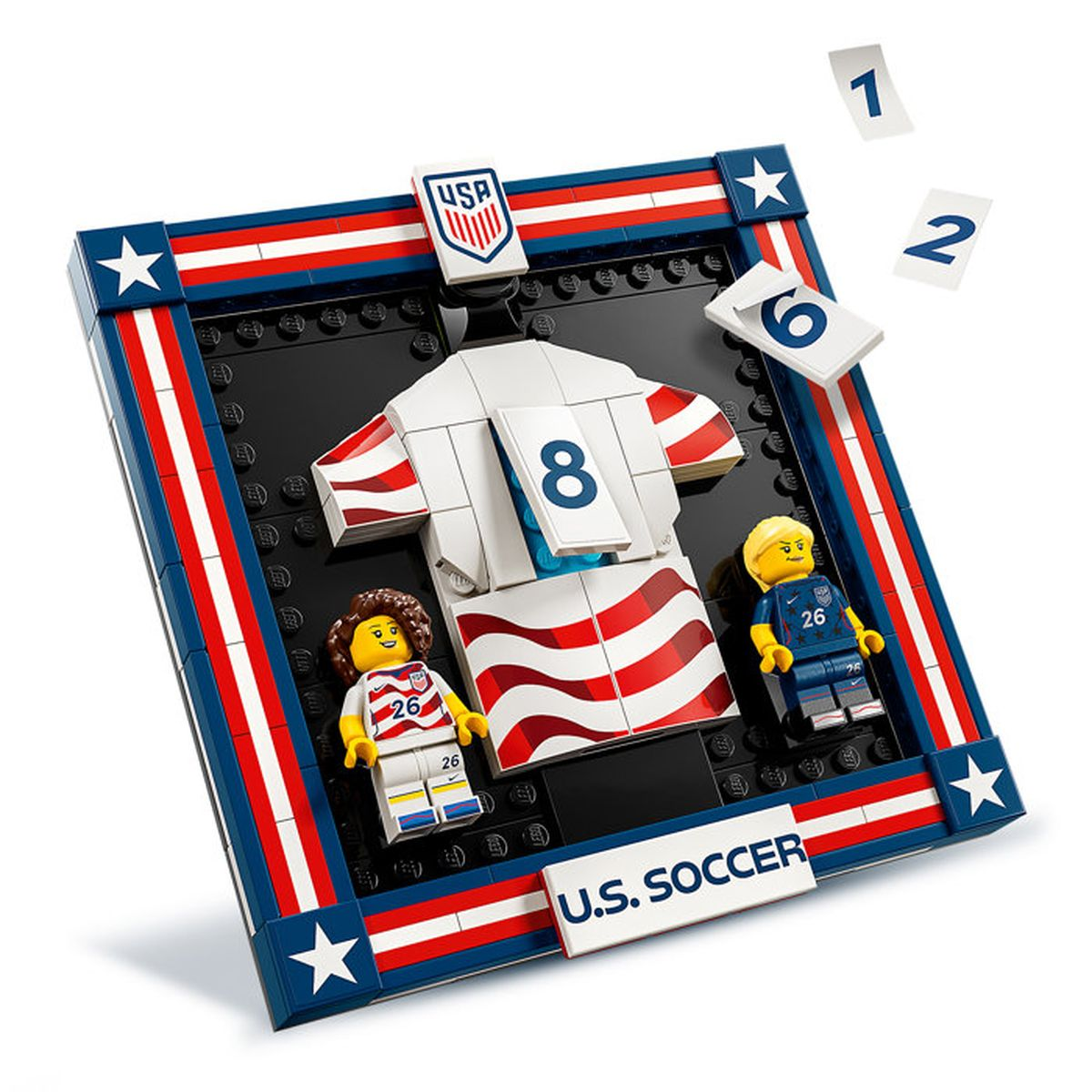 Set LEGO con maglia da calcio, due figure e logo USA su cornice rossa, bianca e blu.