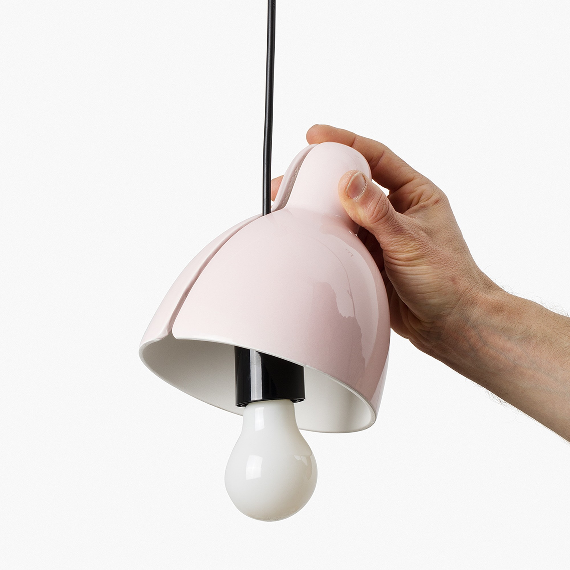 Una mano tiene una lampada rosa con lampadina e cavo nero.