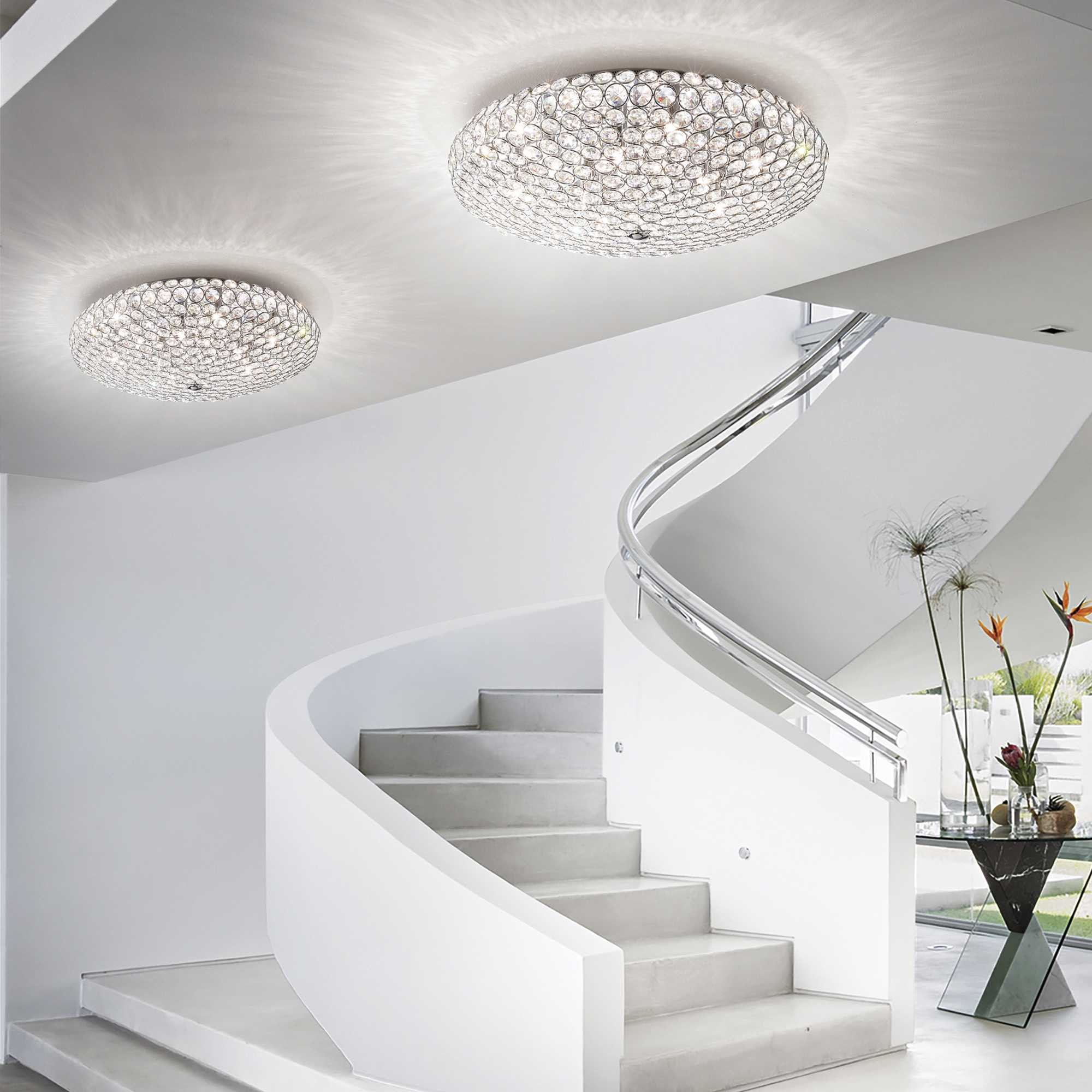 Eleganti lampadari in cristallo illuminano una moderna scala dal design curvo.