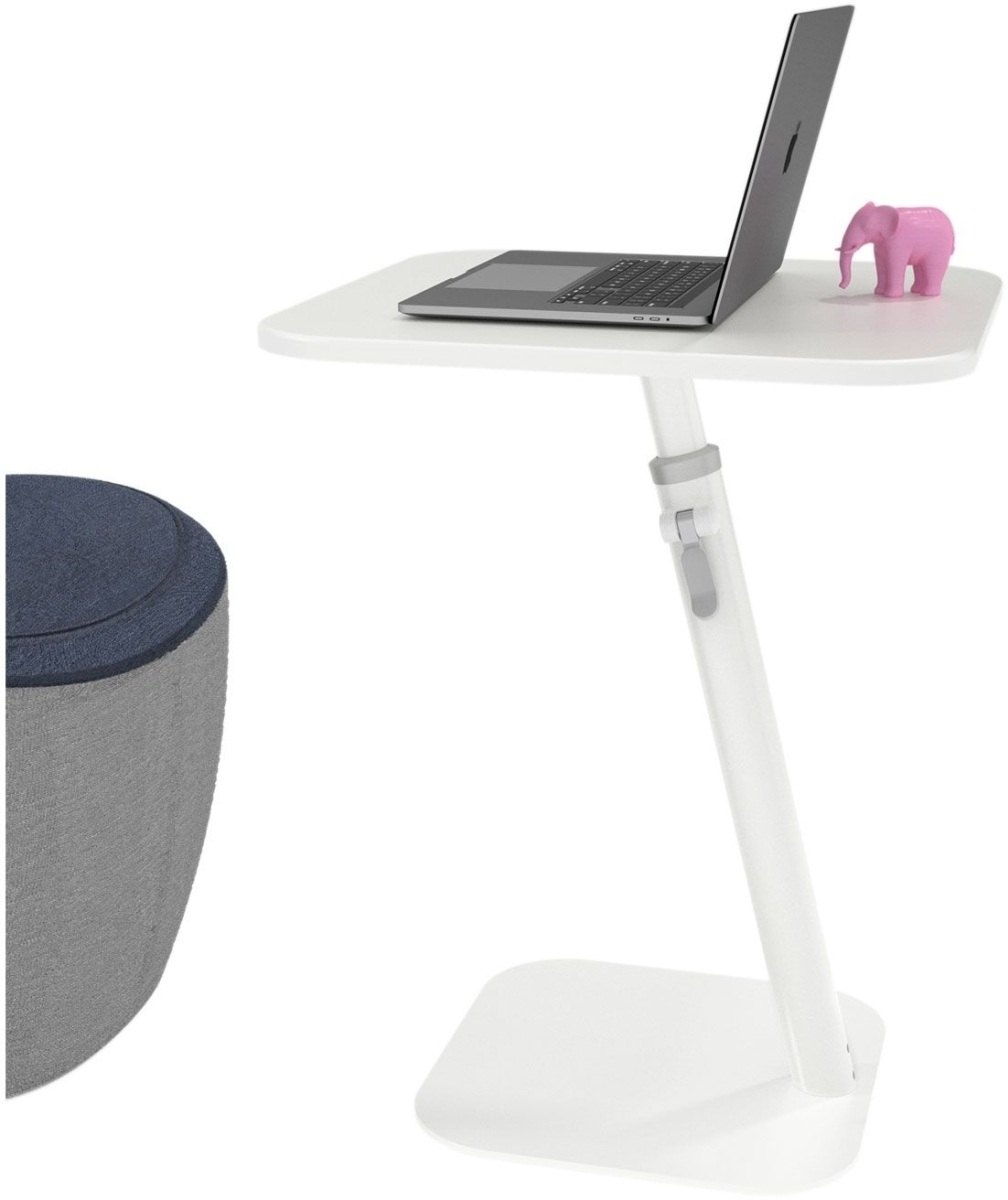 Ein weißer, verstellbarer Tisch trägt einen Laptop und eine rosa Elefantenfigur. Links steht ein blauer Hocker.