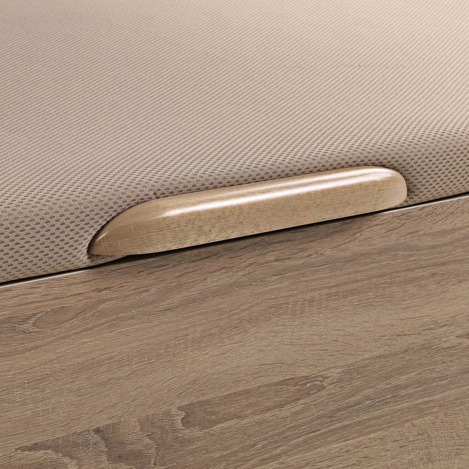Un tirador de madera sobre una superficie de tela beige encima de veta de madera.