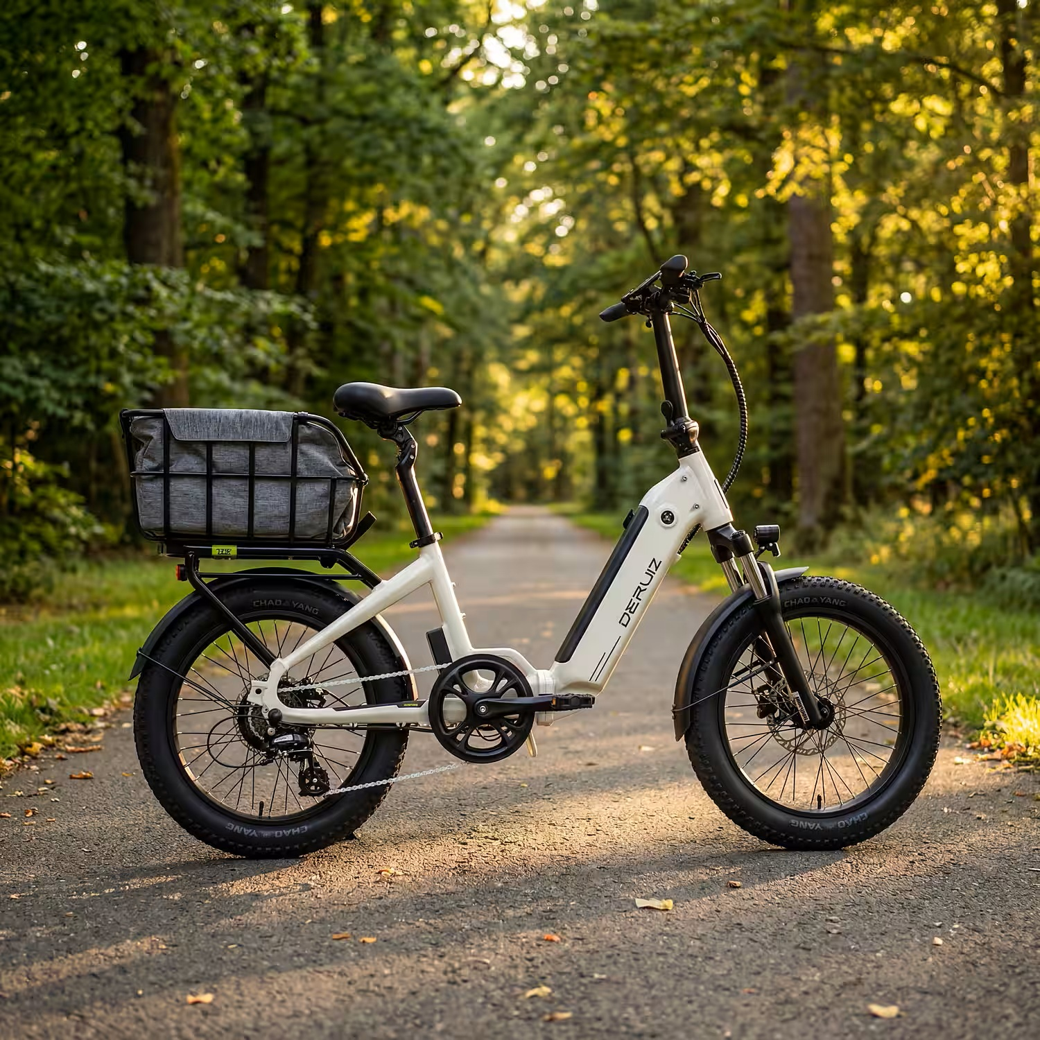 Ein weißes E-Bike mit dicken Reifen und Gepäckträger steht auf einem Weg im Wald.
