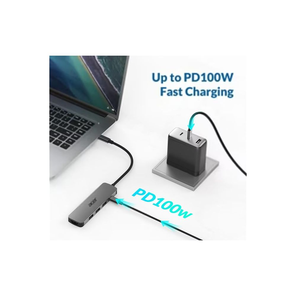Un portátil se conecta a un concentrador USB-C gris conectado a un adaptador de corriente.