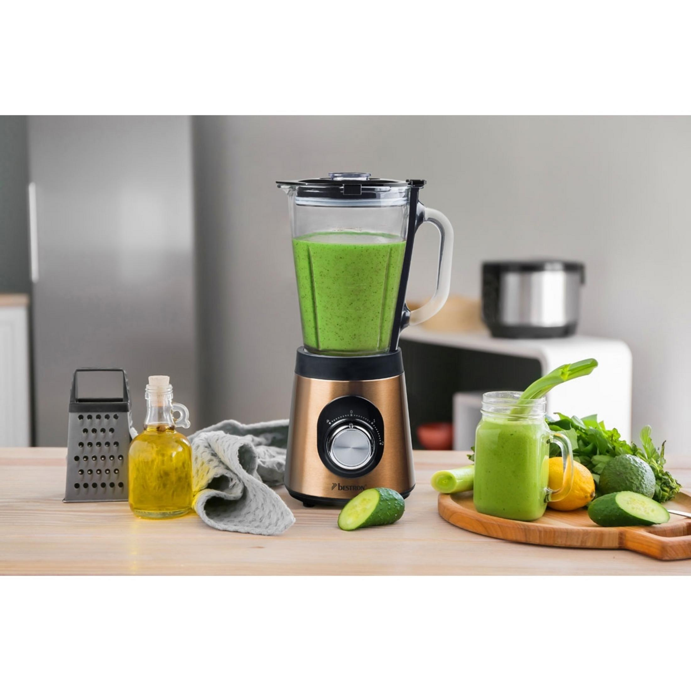 Un frullatore con frullato verde si trova su un tavolo di legno con ingredienti.