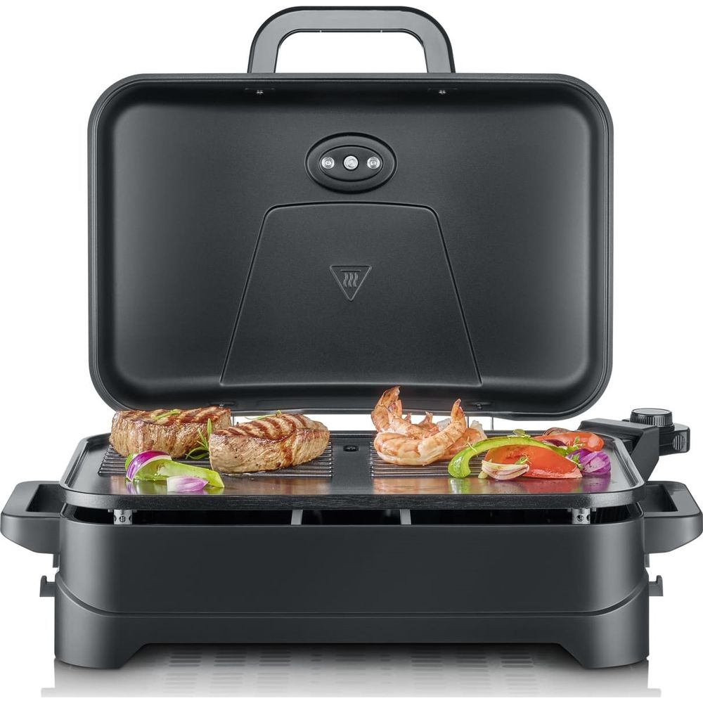 Ein schwarzer Elektrogrill mit geöffnetem Deckel, auf dem Steaks, Garnelen und Gemüse gegrillt werden.