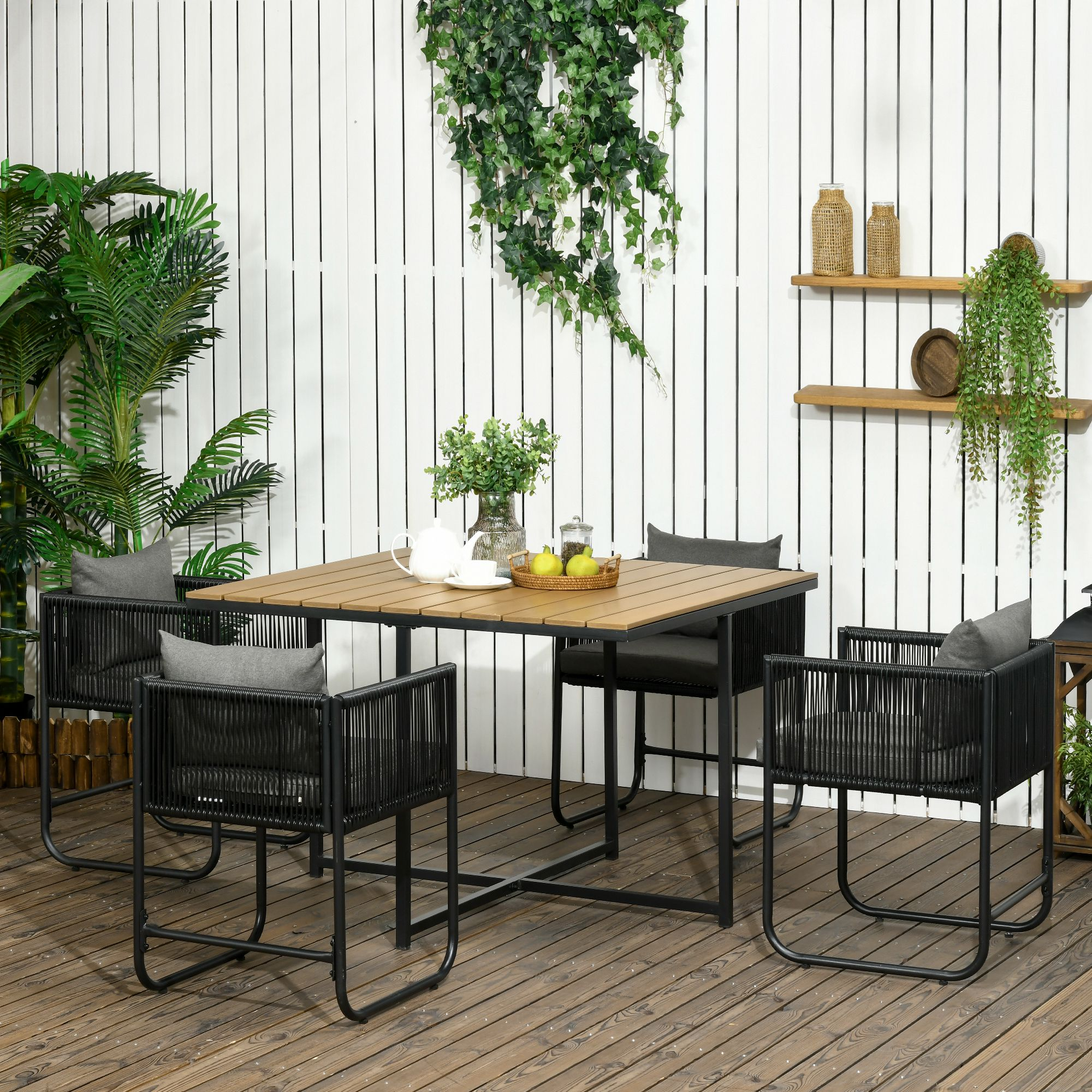 Una mesa de comedor de madera con cuatro sillas negras en una terraza de madera.