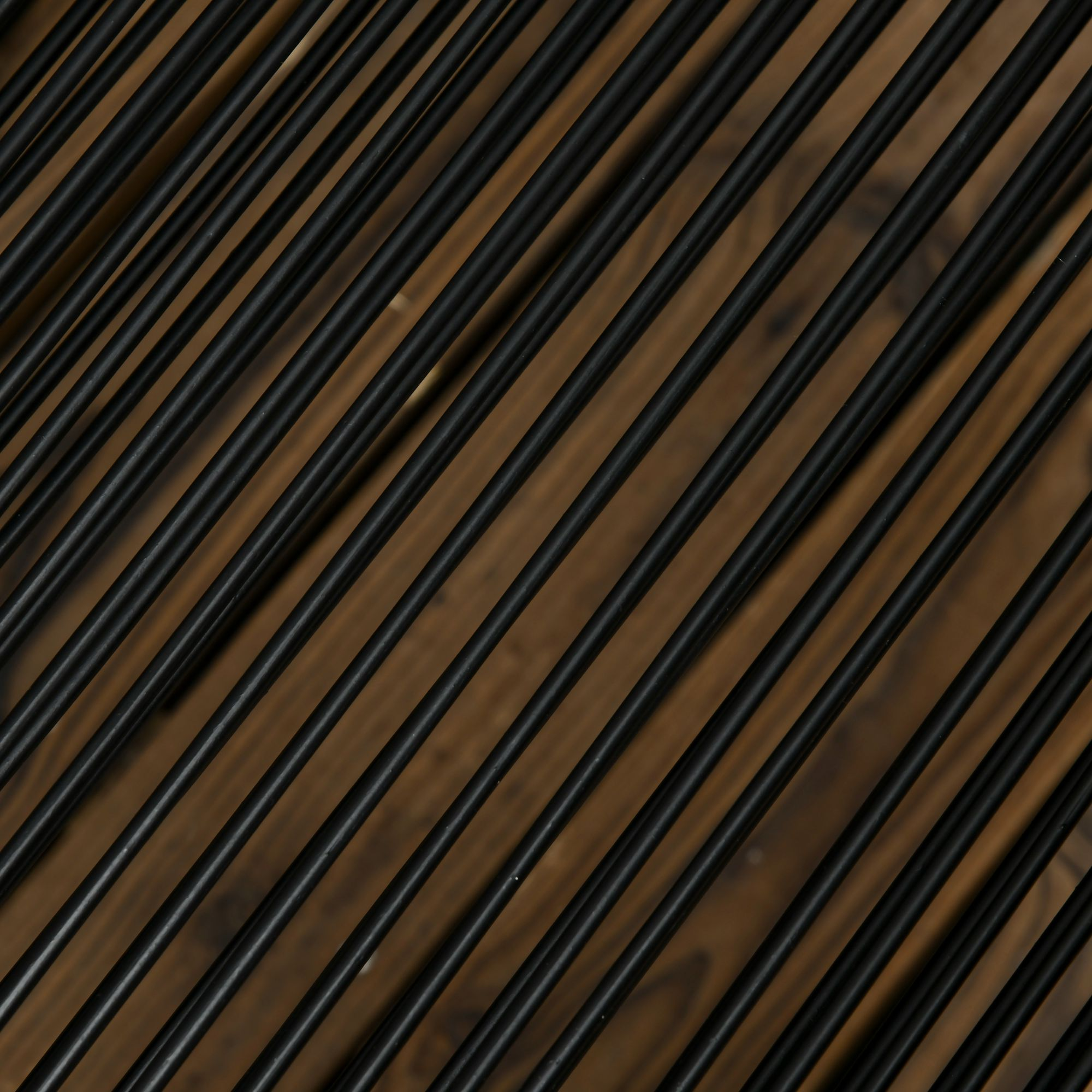 Barras negras corren diagonalmente sobre una textura de fondo de madera marrón.