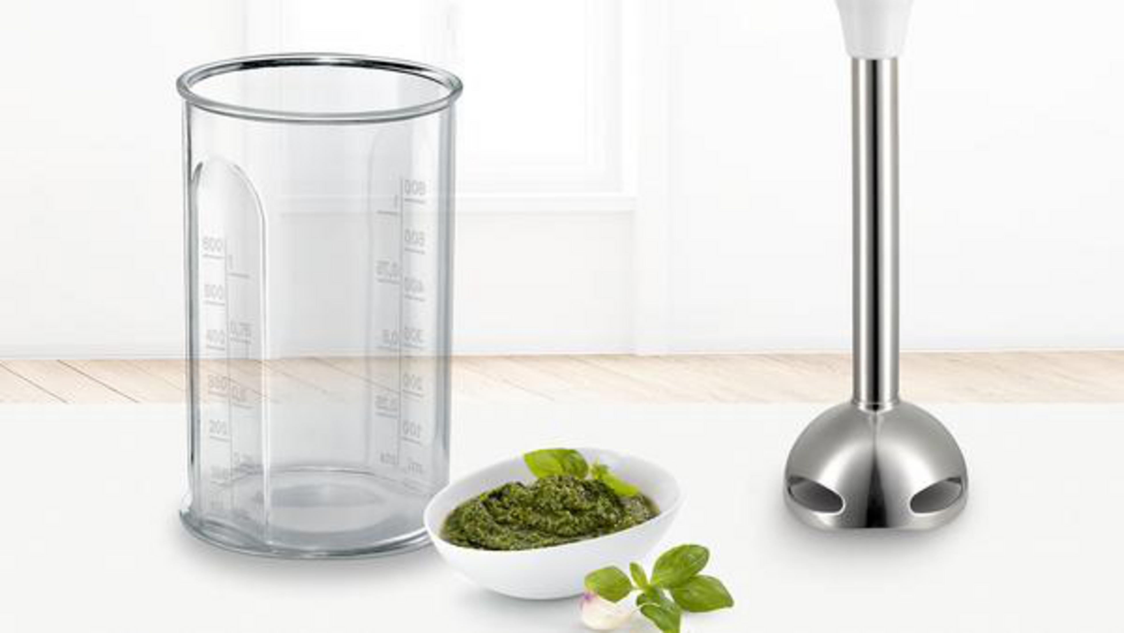Miarka, miska pesto i blender ręczny na białej powierzchni.