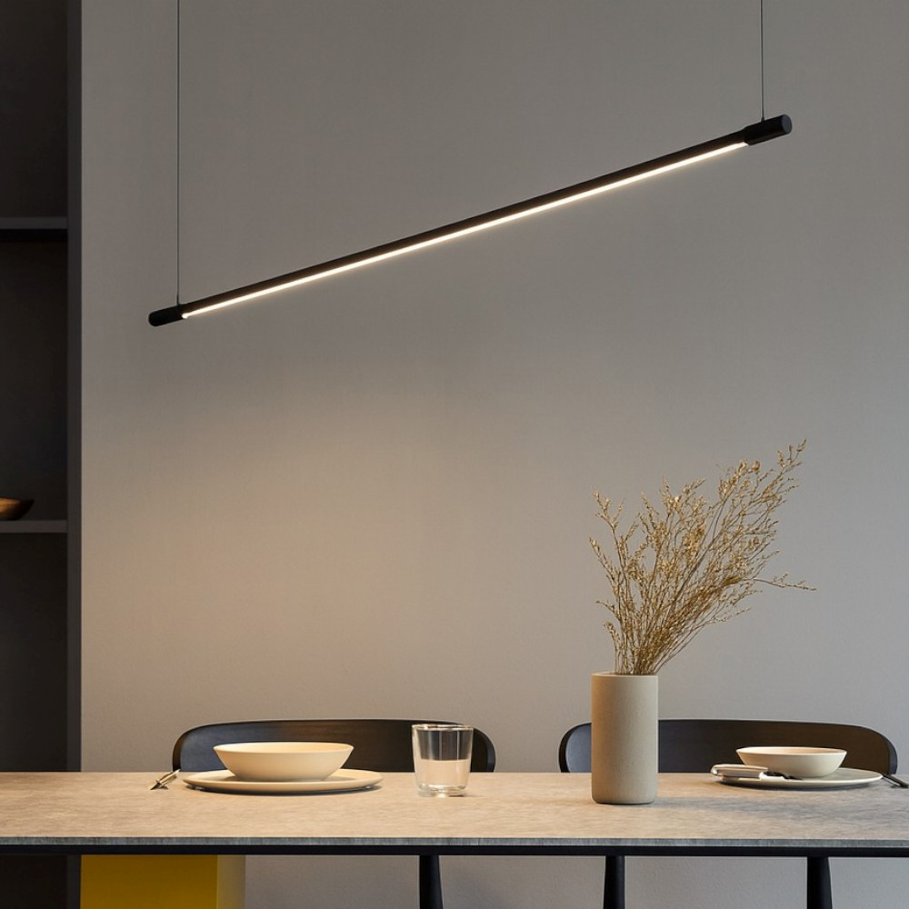 Una lampada a sospensione nera e sottile con illuminazione a LED pende sopra un tavolo da pranzo.