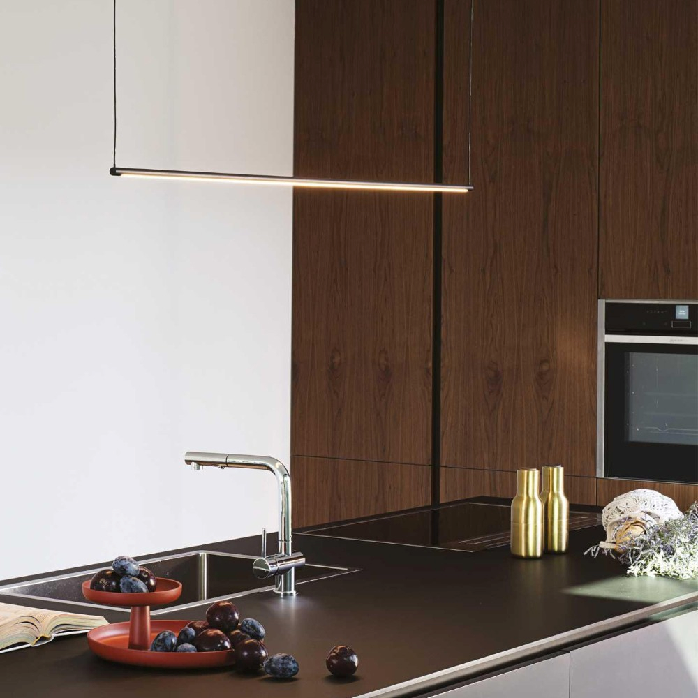 Una cucina moderna con un rubinetto elegante, prugne su un vassoio rosso e mobili in legno.