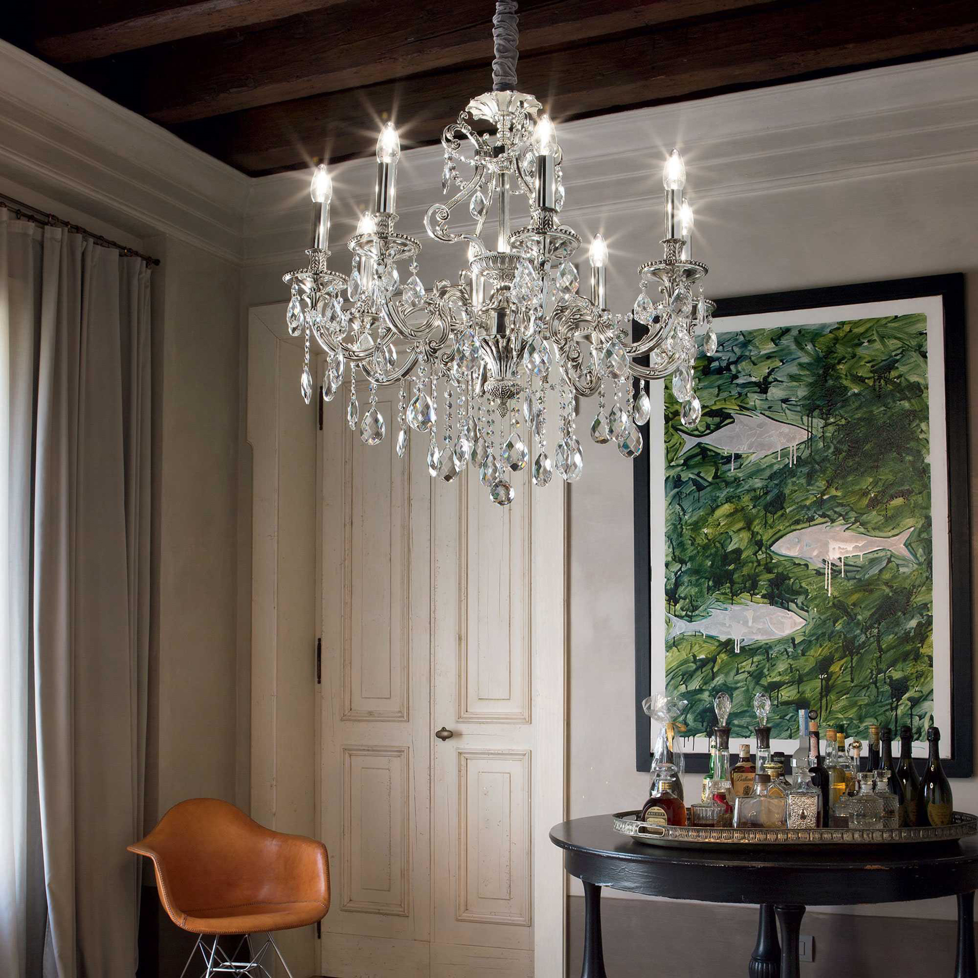 Un lampadario di cristallo appeso sopra un tavolo con bottiglie e un dipinto.