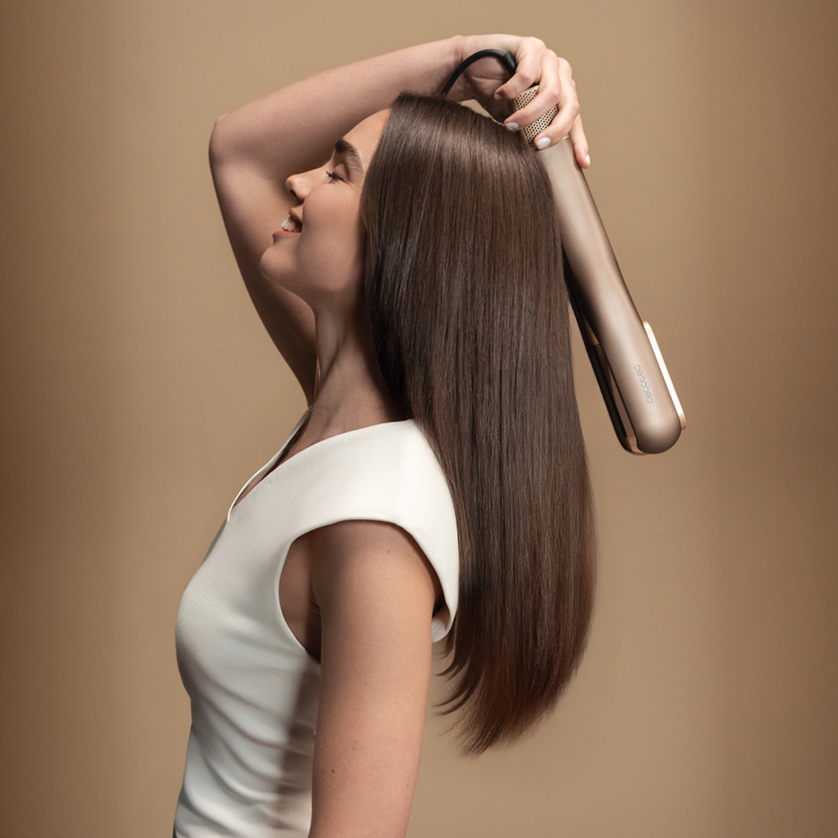Donna con lunghi capelli castani usa una piastra dorata.