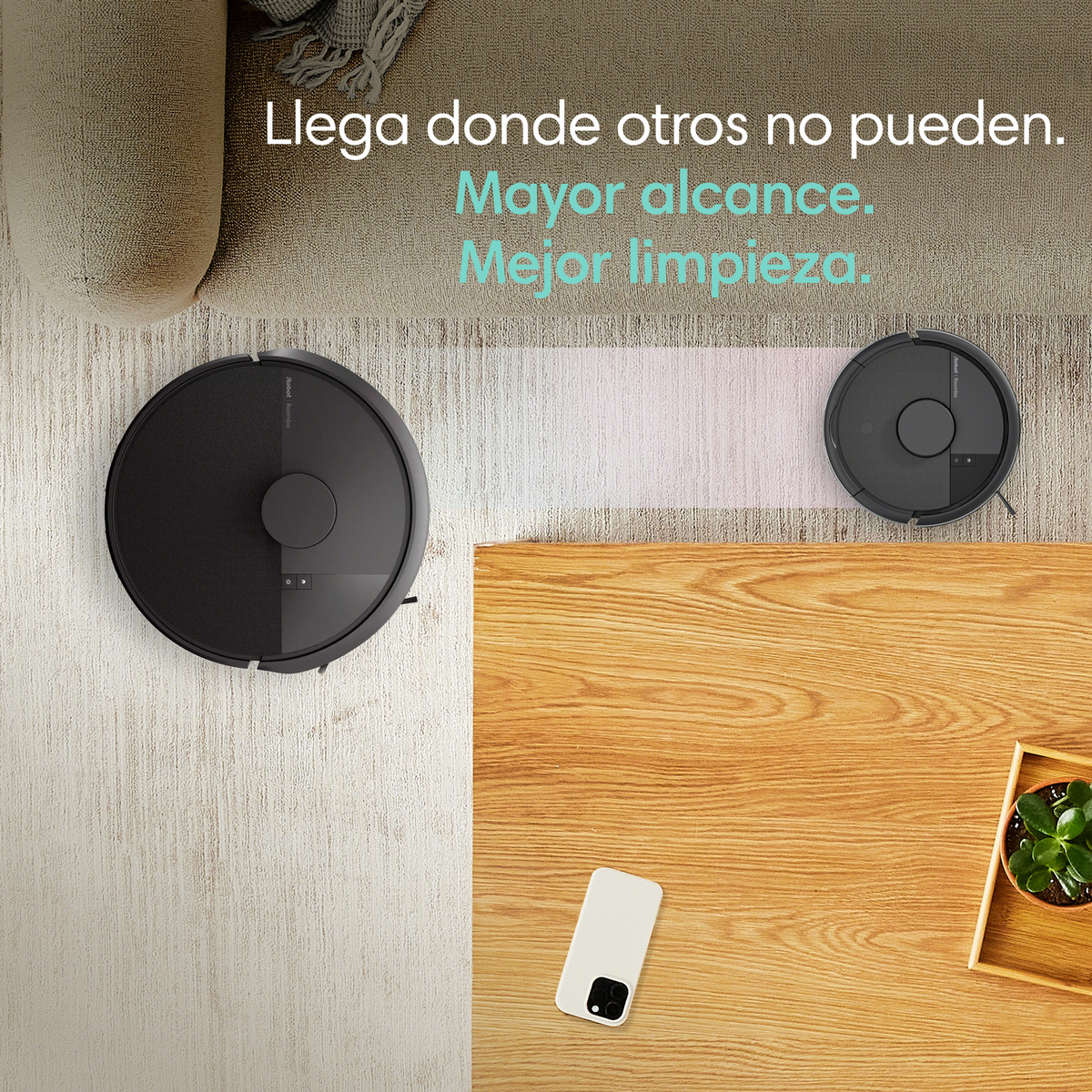 Dos robots aspiradores negros sobre alfombra clara y mesa de madera.