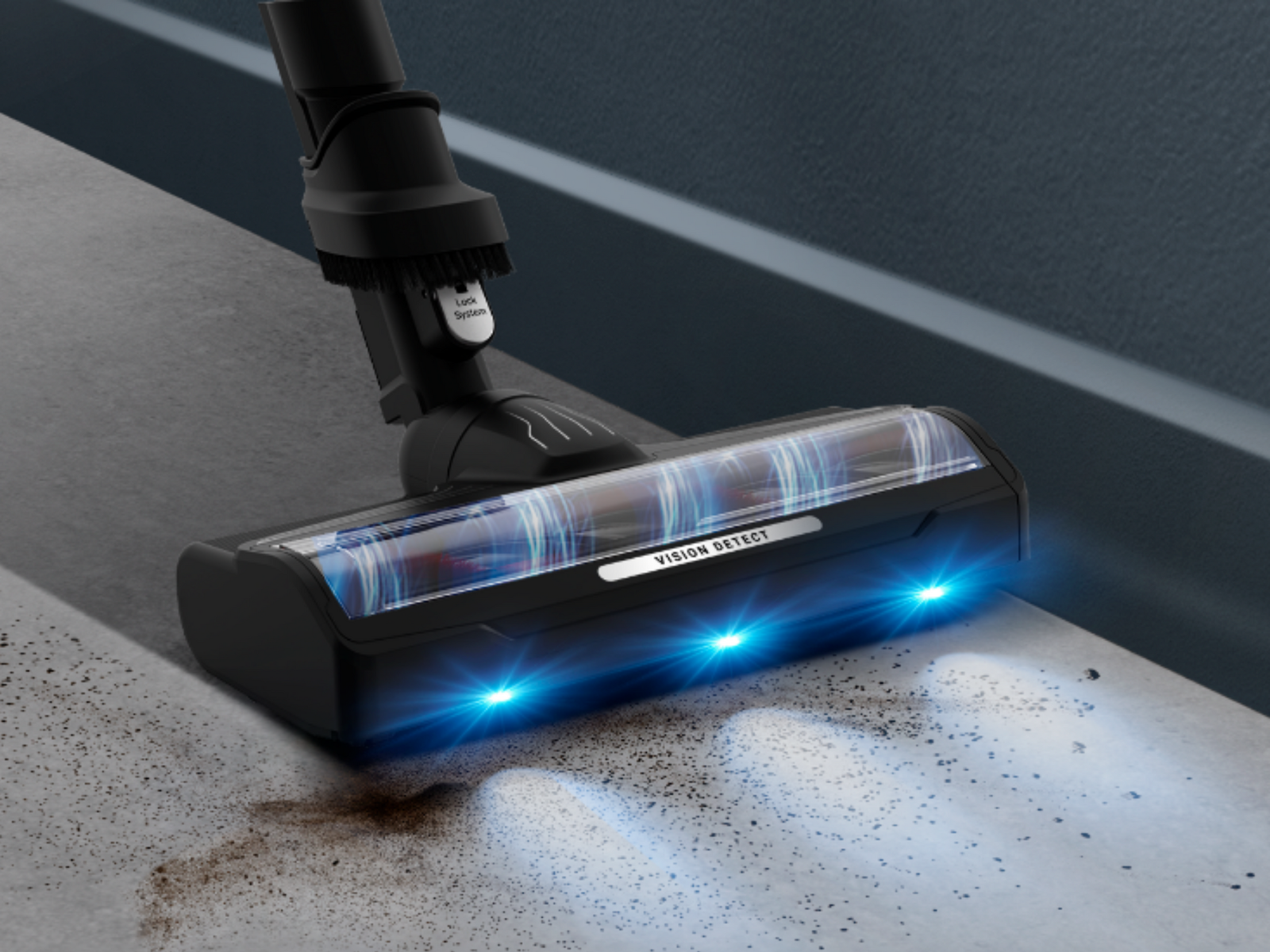 Una testina aspirapolvere nera con luci blu pulisce lo sporco su pavimento in cemento.