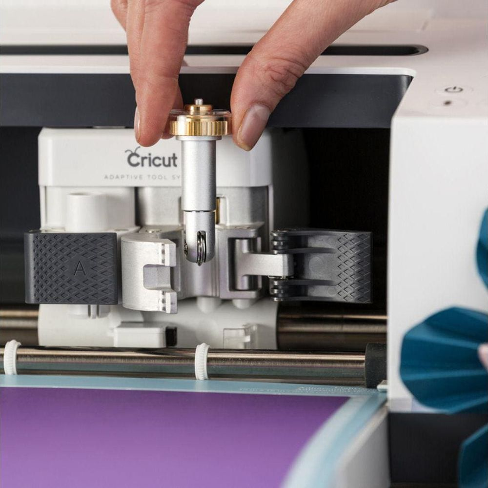Una mano inserta una cuchilla de corte en una máquina Cricut.