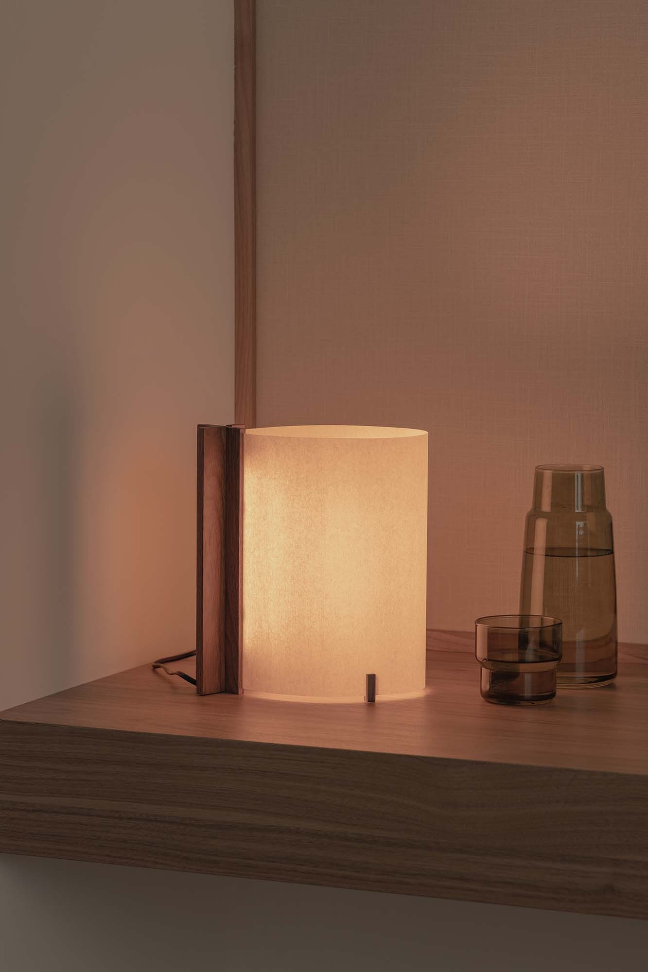 Lampada da tavolo illuminata con dettagli in legno accanto a due contenitori di vetro.