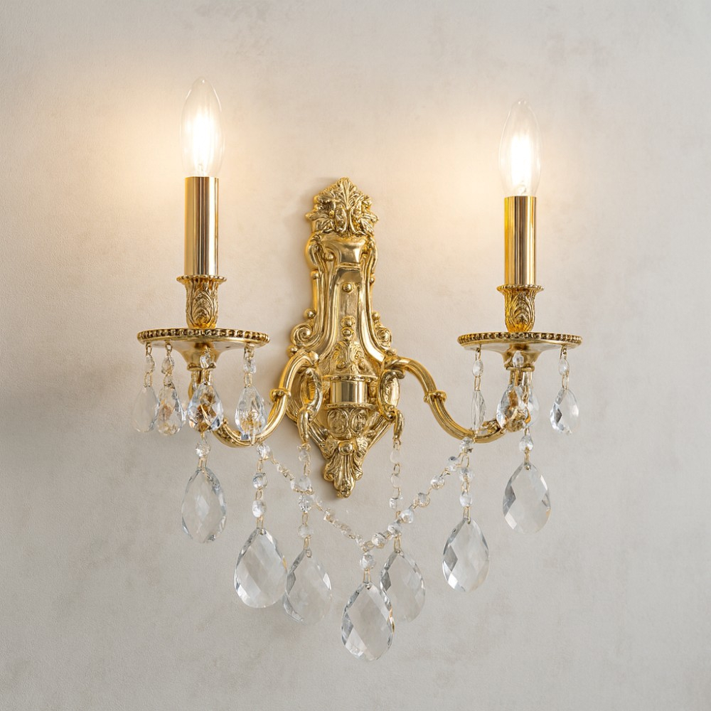 Applique da parete doppia in ottone ornato con gocce di cristallo e lampadine a candela accese.