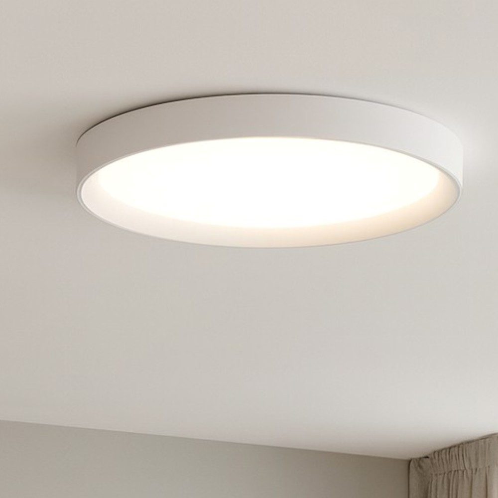 Una plafoniera rotonda bianca, a filo, con illuminazione brillante su un soffitto bianco.