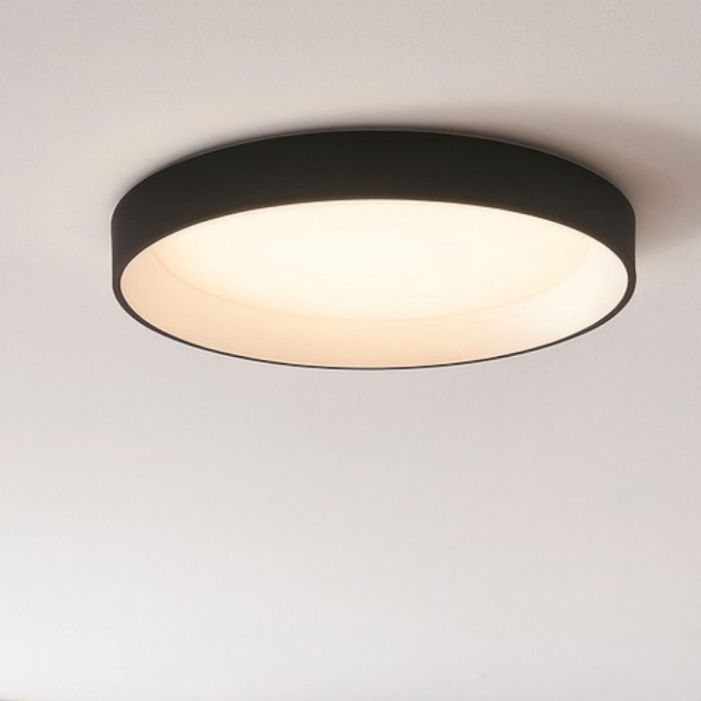 Una moderna lampada da soffitto nera con un diffusore rotondo illuminato.
