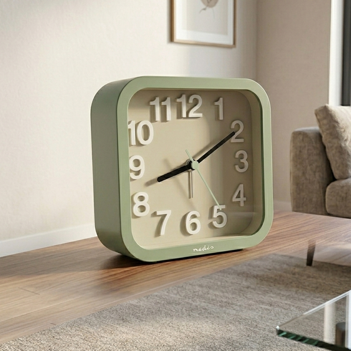 Una sveglia quadrata verde con numeri bianchi è su un tavolo di legno.