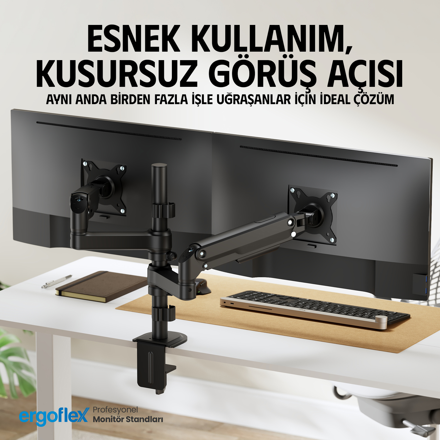 Siyah kollu, iki monitörlü bir masa. Klavye ve not defteri mevcut.