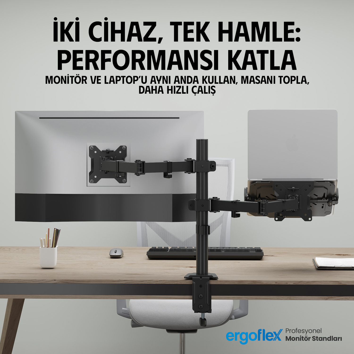 Çift kollu montaj aparatına bağlı monitör ve laptoplu bir masa.