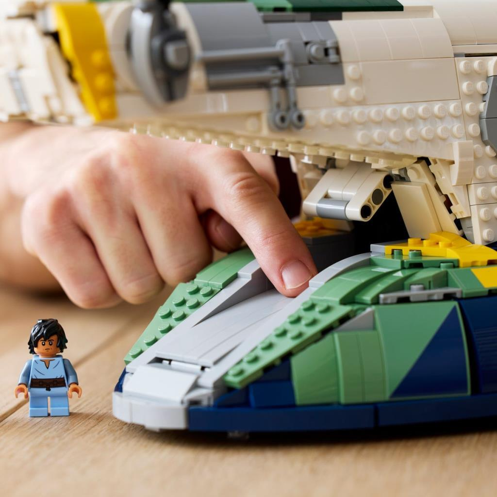 Una mano tocca un'astronave Lego verde e blu, accanto a una minifigure.