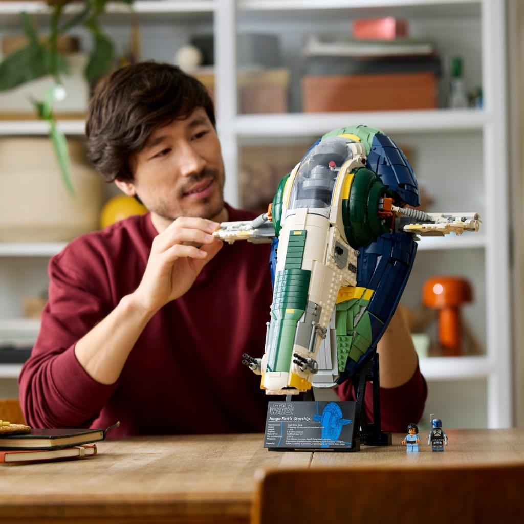 Uomo costruisce un'astronave Lego dettagliata in blu, verde e bianco.
