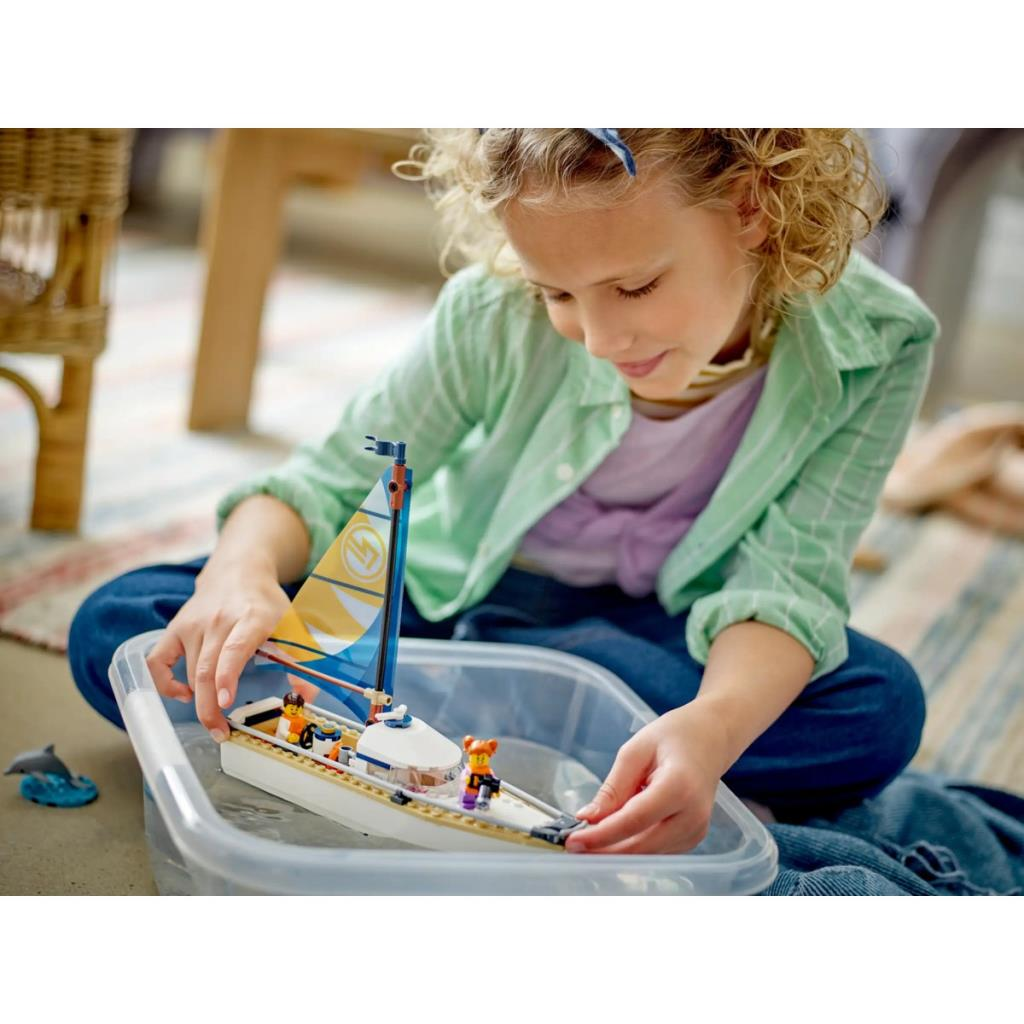 Een meisje speelt met een speelgoedzeilboot in een plastic bak op de vloer.