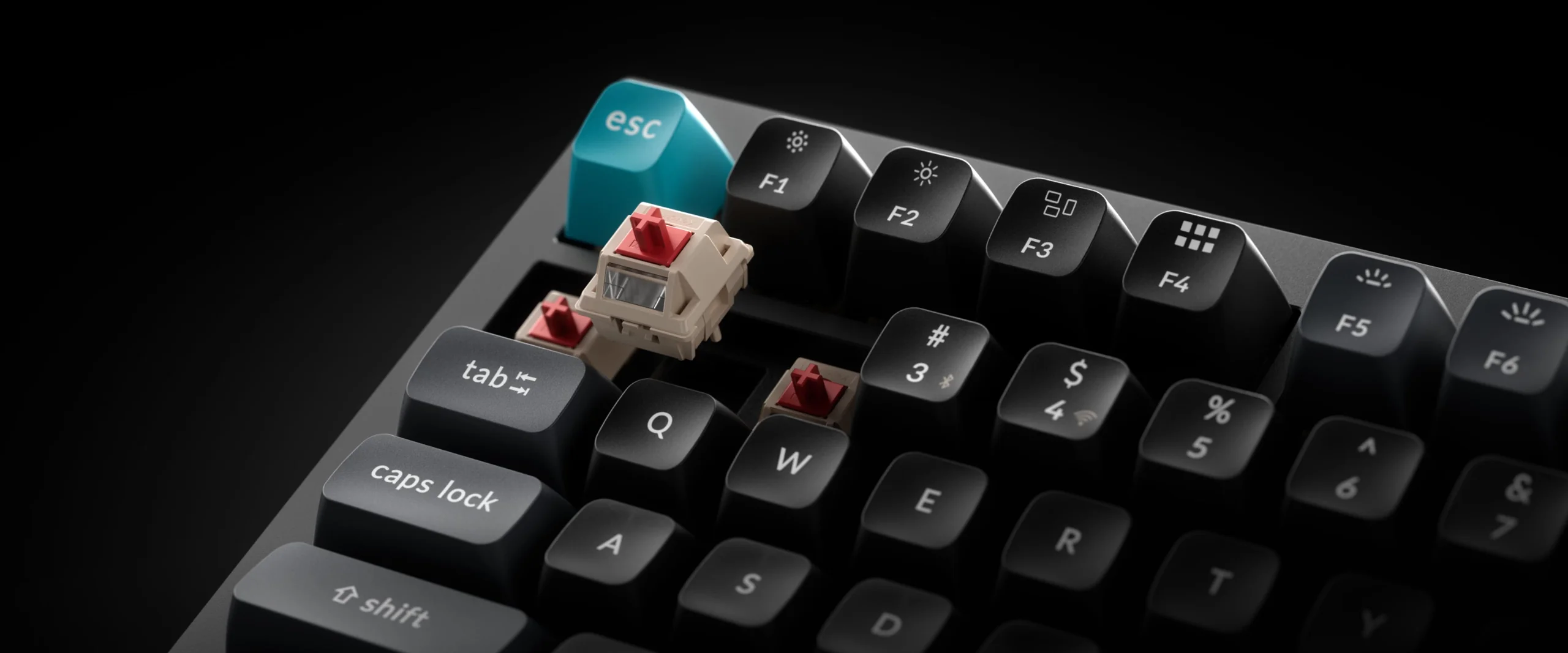 Zbliżenie klawiatury mechanicznej z odsłoniętymi przełącznikami. Turkusowy klawisz esc.