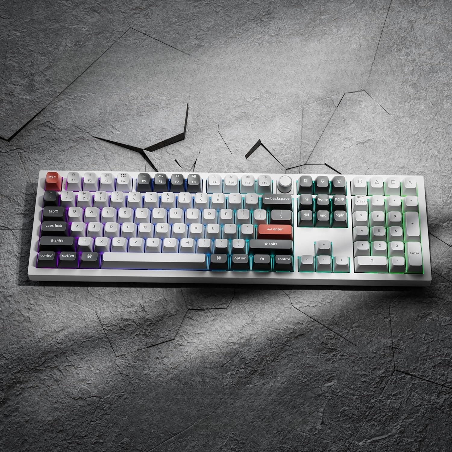 Biała klawiatura mechaniczna z podświetleniem RGB na ciemnej, spękanej powierzchni.
