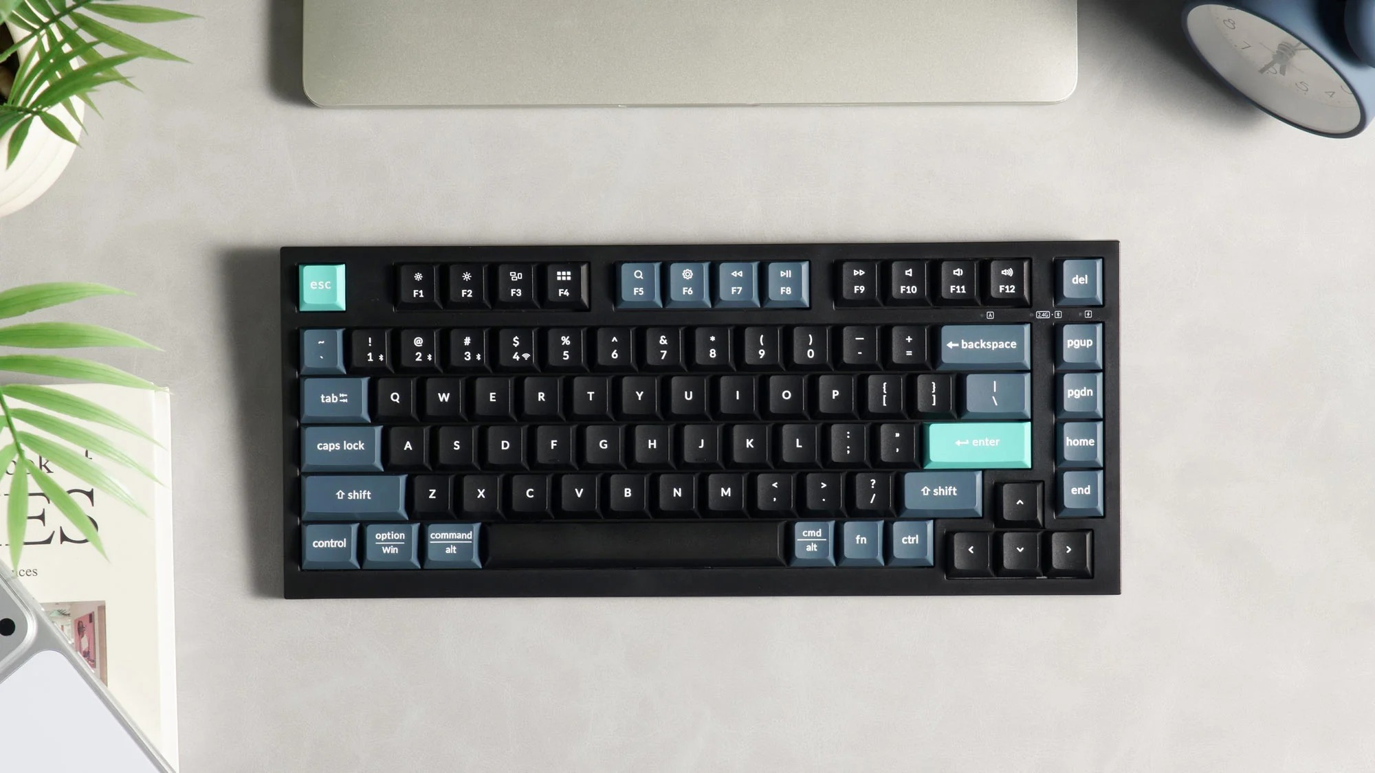 Czarna klawiatura z niebieskimi i miętowo-zielonymi klawiszami na stole.