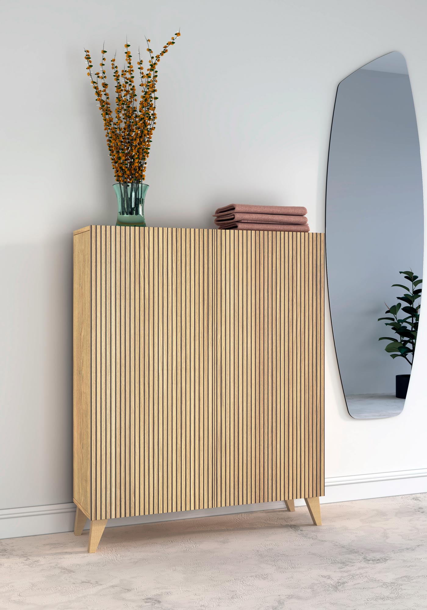 Un mueble de madera con puerta acanalada, coronado por un jarrón de flores naranjas y toallas dobladas.