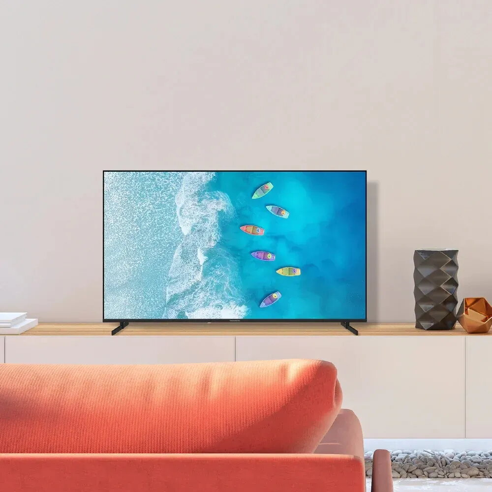 Un televisor muestra barcos coloridos en agua azul y una costa.