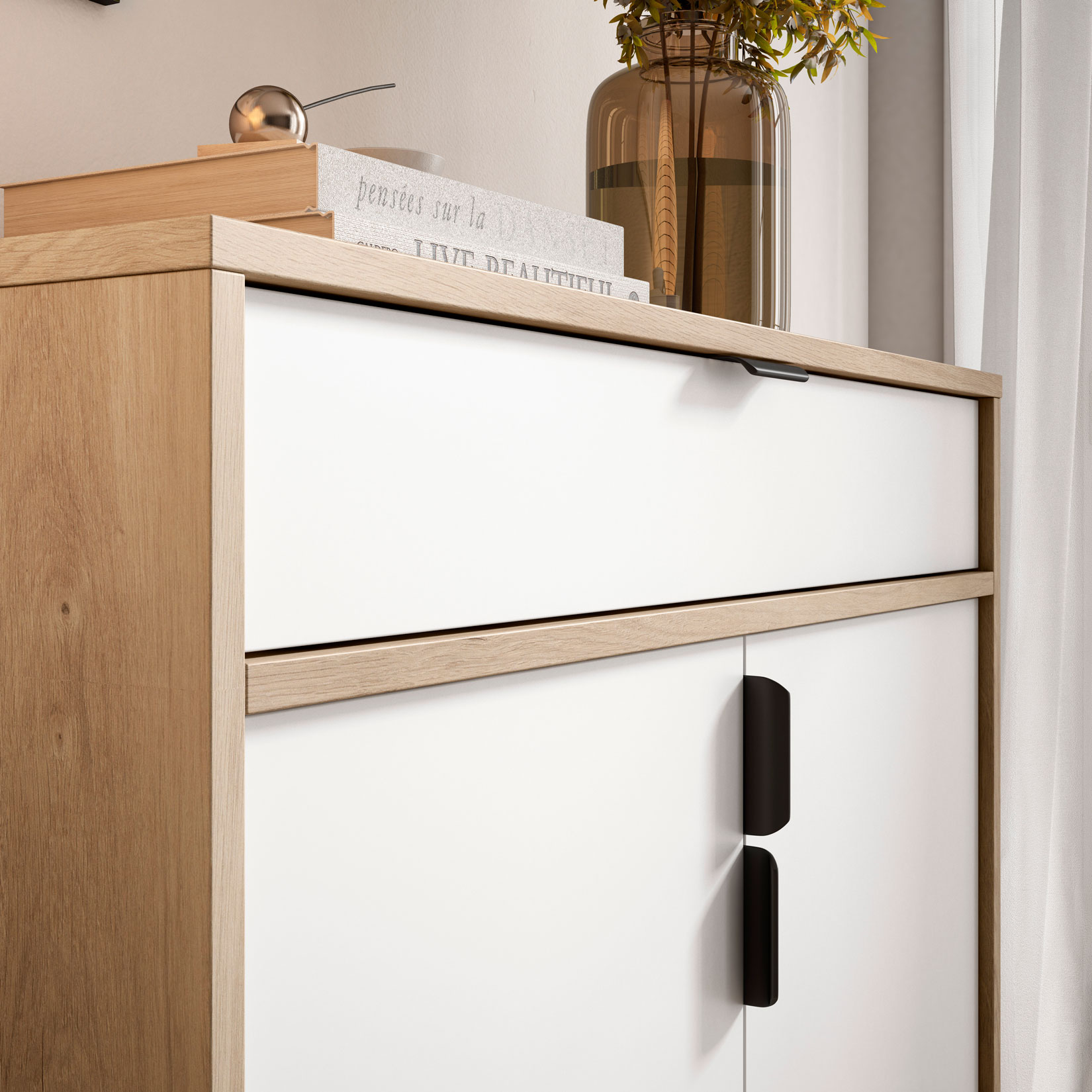 Un mueble blanco con detalles de madera y tiradores negros. Libros y un jarrón encima.