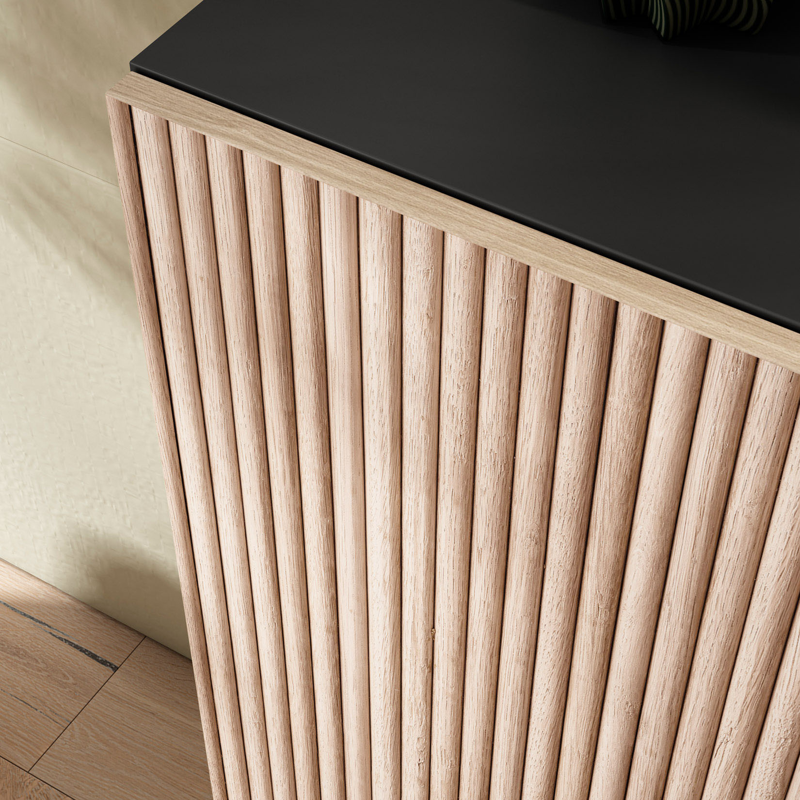 Mueble de madera con frente de listones y tapa negra, junto a una pared.
